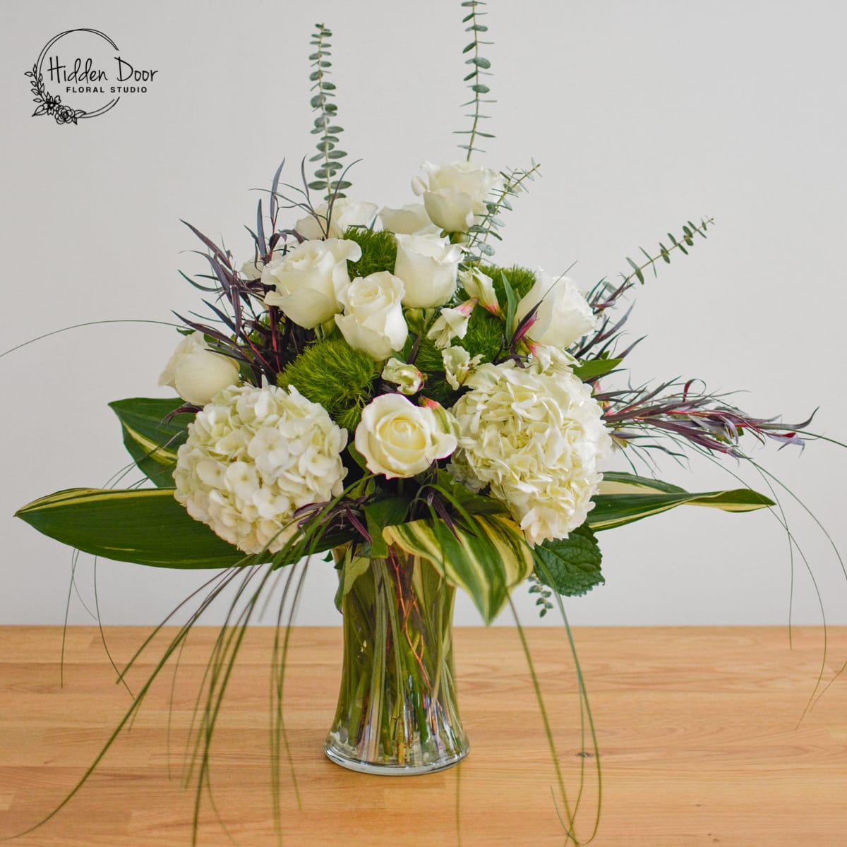 Fantasy Fantasy - Embark on a journey into a realm of enchantment with our extraordinary floral creation, "Fantasy." This beautiful arrangement transports you to a world where dreams come alive, imagination dances with beauty, and every petal tells a magical story. Imagine a stunning glass vase reaching toward the sky, elegantly showcasing a symphony of delicate blooms. "Fantasy" is a true masterpiece, meticulously designed with an exquisite combination of white hydrangeas, velvety white roses, and vibrant green dianthus. Each petal and stem is carefully selected to create a harmonious composition that dazzles the senses. But "Fantasy" doesn't stop there. It evolves with the seasons, embracing the ever-changing tapestry of nature. Adorned with carefully chosen seasonal blooms and lush greens, this arrangement becomes a living work of art, reflecting the beauty of each passing moment.