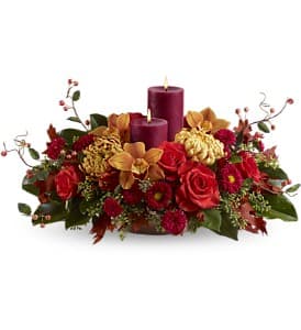 Warm and Wonderous - Warm, wondrous and bright - this grand Thanksgiving centerpiece, featuring two pillar candles surrounded by roses, orchids and more in shades of red, bronze and orange, will light up your holiday table with its beauty! Set the stage for a heartfelt holiday celebration.