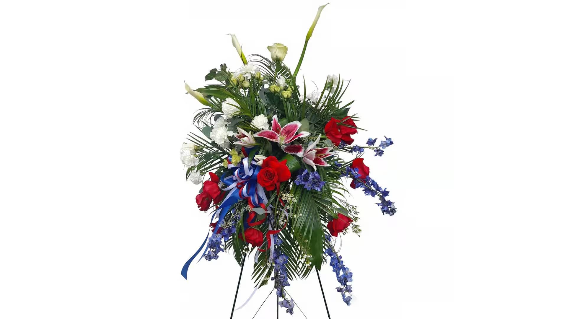 Love memorie  - Our &quot;love memory&quot; funeral flower arrangement is a heartfelt tribute, thoughtfully curated with an exquisite blend of white carnations, red roses, pink star lilies, calla lilies, wax flowers, eucalyptus, blue delphinium, and spray roses. This elegant arrangement includes a white, red, and blue ribbon to honor your loved one's memory and a sturdy metal stand for dignified display.