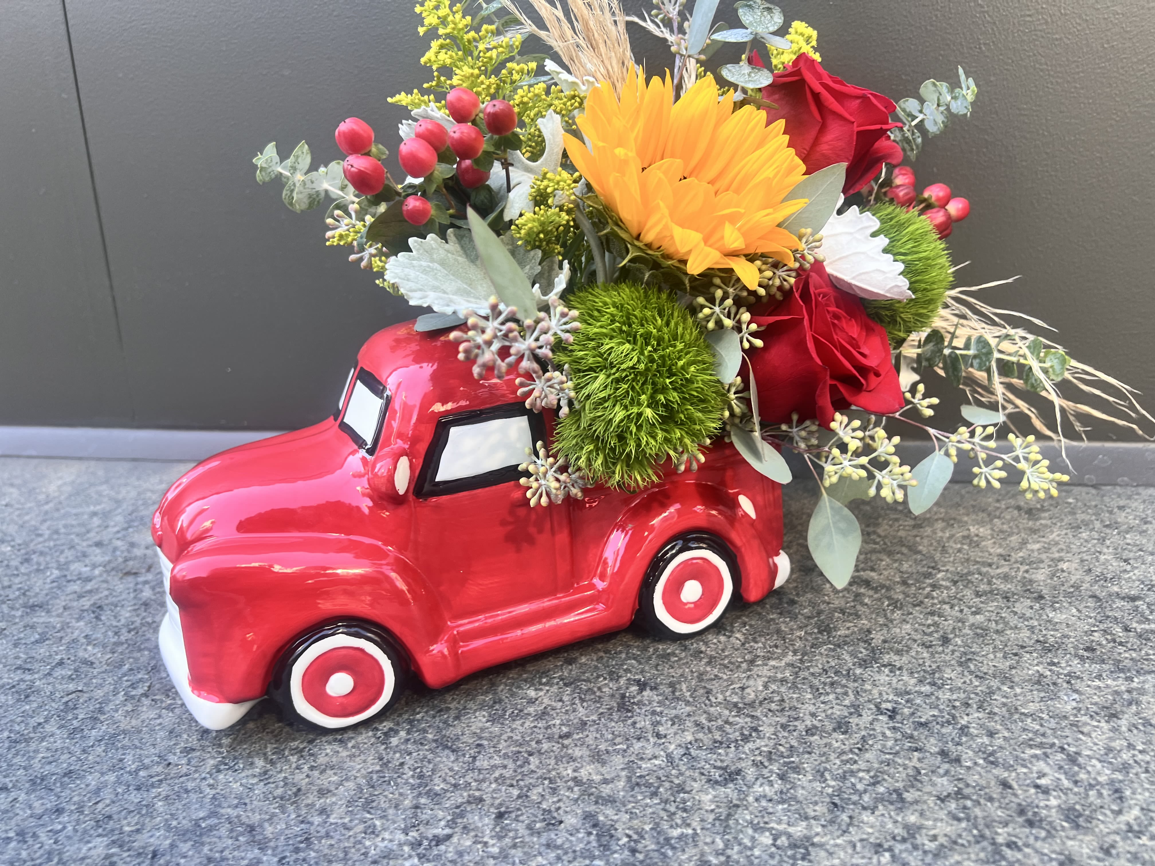 Farmers Truck  - A collective ceramic farmers red truck, 11” long by 7” tall , fill with a mixture of seasonal flowers includes coffee  beans, seed eucalyptus, dusty miller, roses, mums, pompon grass. 