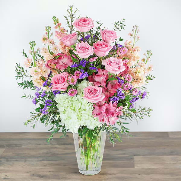 Fantasy Garden - The product includes roses, hydrangeas, chrysanthemums, eucalyptus, baby's breath and some green leaves, and is placed in a glass vase.