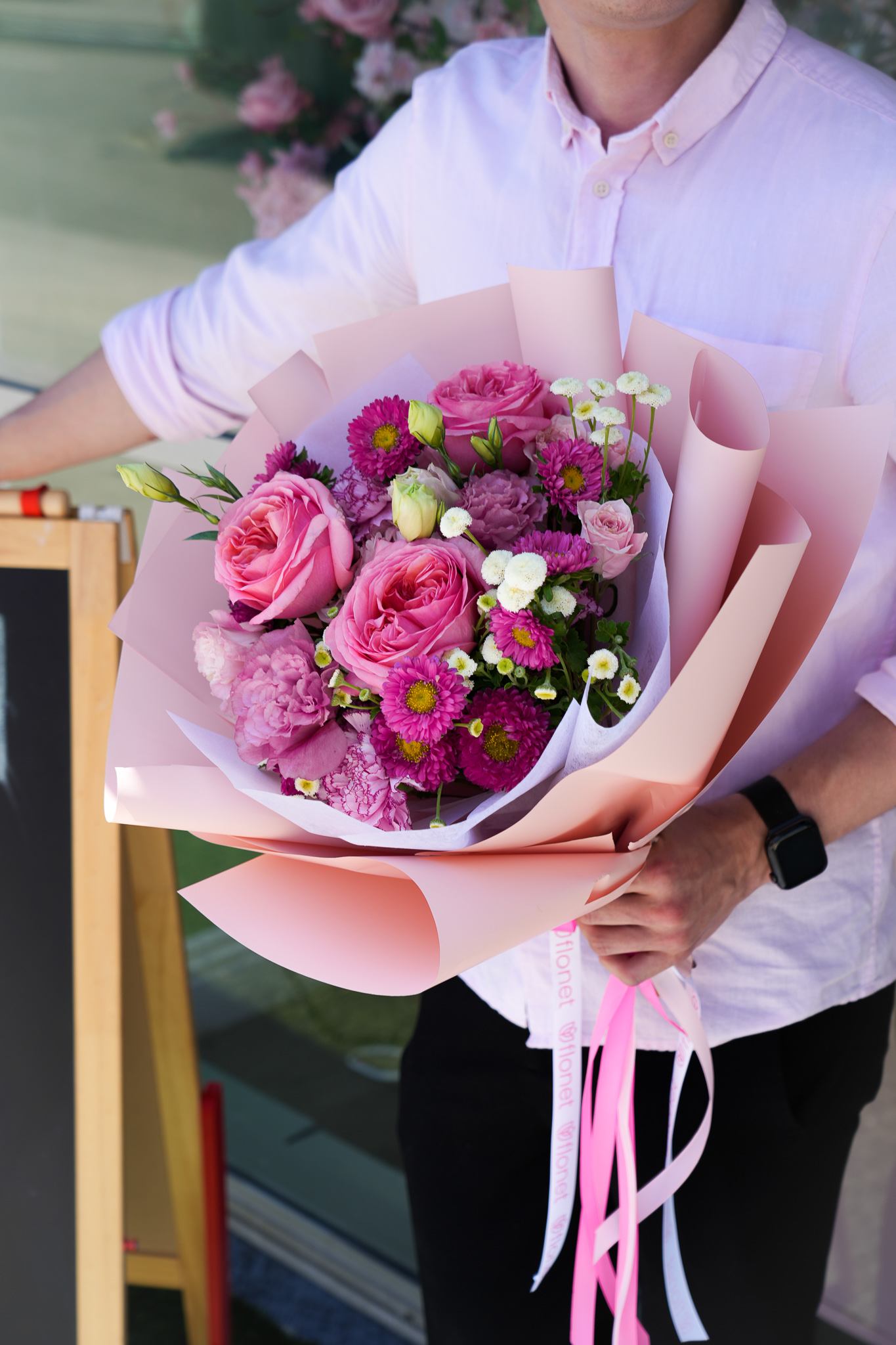 Rosy Radiance Bouquet Rosy Radiance Bouquet - The Pink Harmony Bouquet is a stunning arrangement featuring vibrant pink roses, delicate pink peonies, and rich purple chrysanthemums. Accentuated with white flowers and lush green foliage, this bouquet is beautifully wrapped in soft pink paper, adding an extra touch of elegance. Perfect for expressing love, admiration, or simply bringing joy to someone special, the Pink Harmony Bouquet is a captivating choice for any occasion.