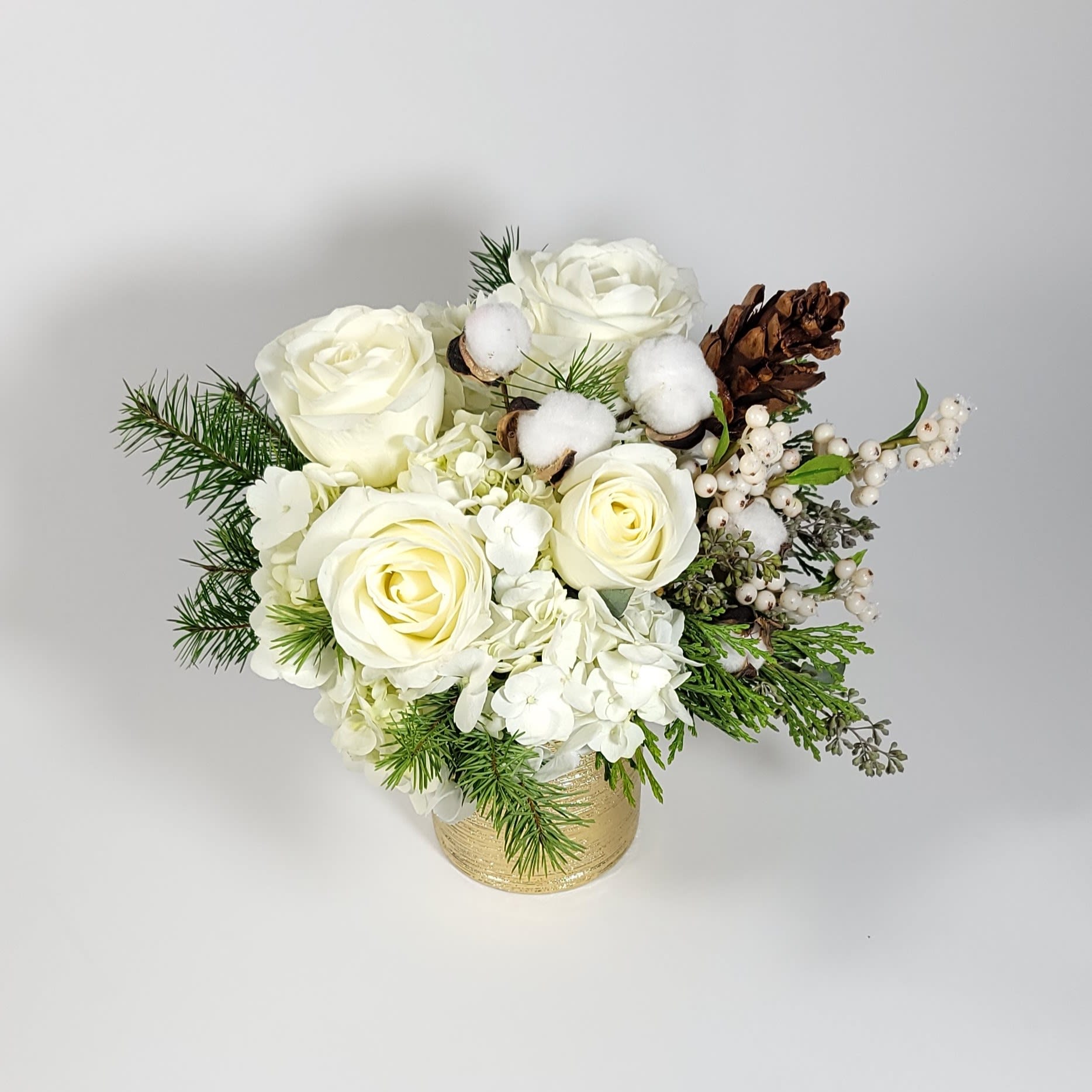 White Christmas  - In a gold vase, an arrangement made of 4 roses, hydrangeas, white berries, and greenery to complement the design.