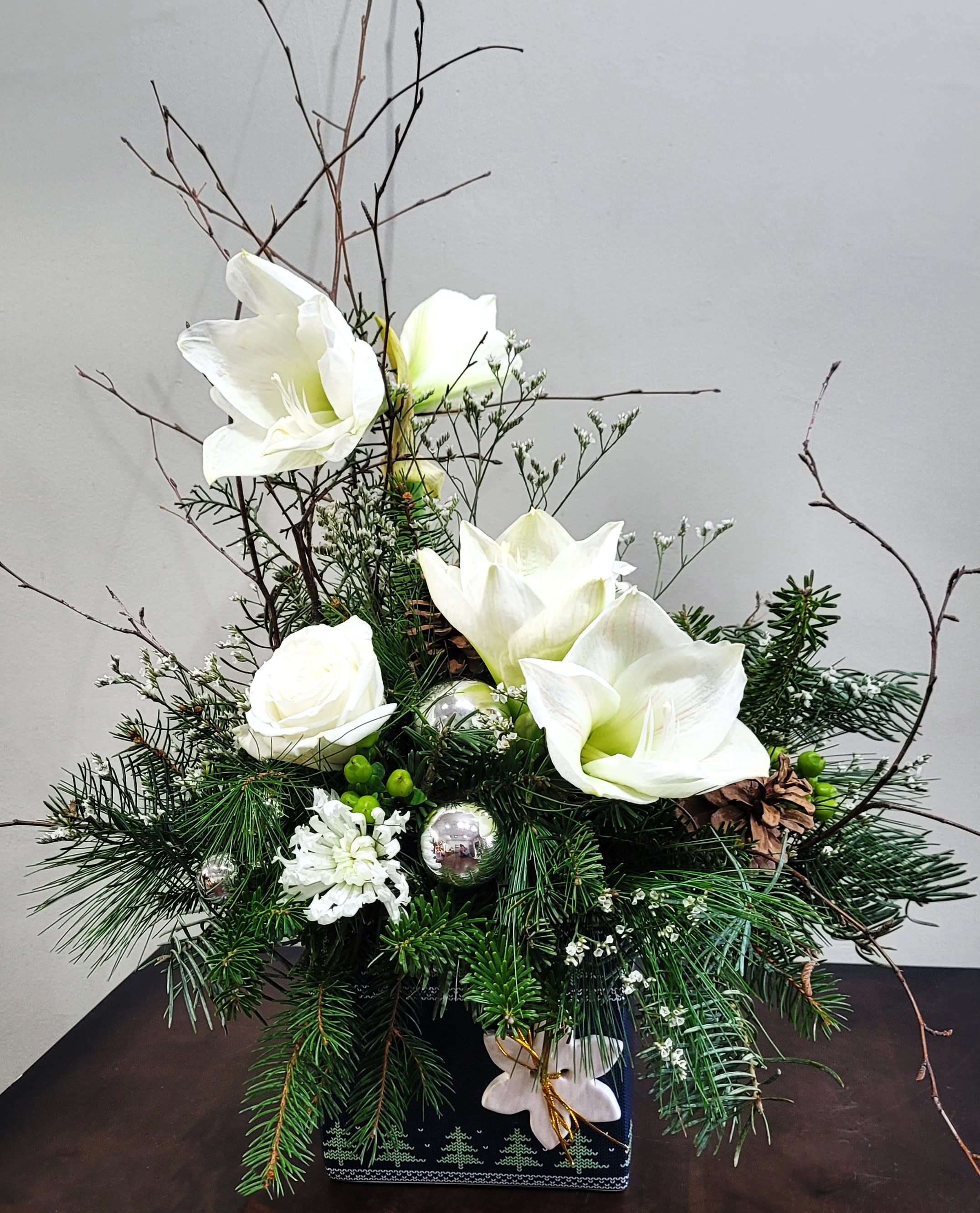 Holiday Joy I - Bring all the festivities of the holidays home with seasonal long lasting Amaryllis blossoms complimented with Roses, Genesta, pine cones, baubles and frangrant pine greens arranged in a large 5'' holiday glazed ceramic cube vase. 