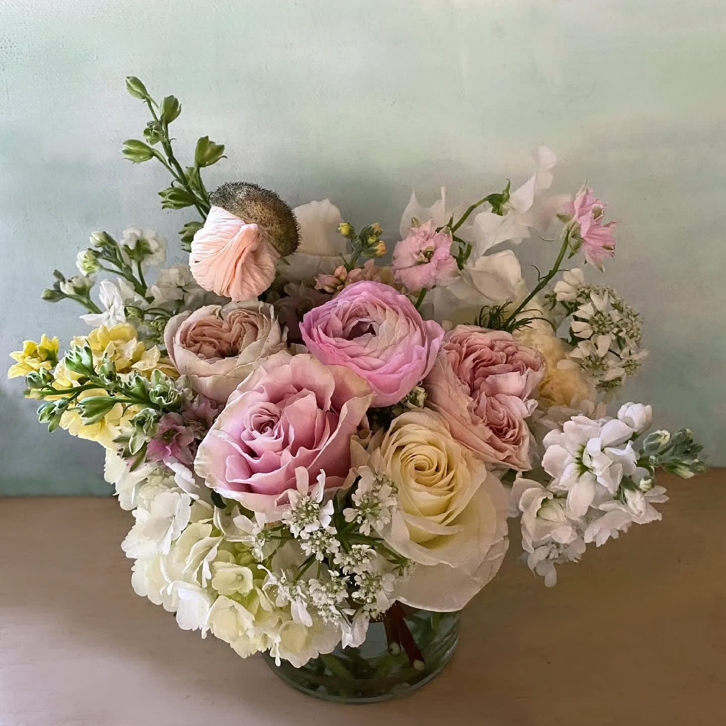 Ichika arrangement - In Japanese Ichika (一千花) means: “One thousand flowers''. A very aesthetic mix of white, light pastel yellows and light pinks in this simple yet detailed poetic arrangement, perfectly suited to give as a pretty flower gift. Spring-like and light, full of beautiful seasonal flowers like stock, ranunculus, poppies, sweet peas etc. Arranged in a 5' by 5' clear vase. Choose deluxe for a fuller arrangement with more stems or Premium for a larger arrangement arranged in a 6&quot; by 6&quot; clear cylinder vase