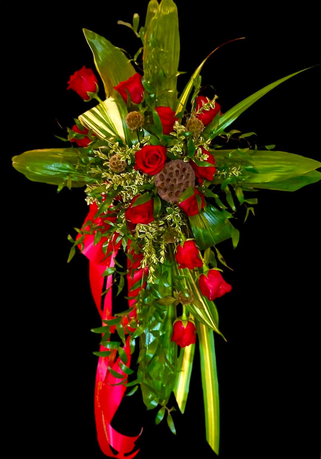 Ti Leaf & Roses Sympathy Cross Ti Leaf & Roses Sympathy Cross - This unique design is composed of various tropical foliage and beautiful lush Red Roses. The body of the cross is composed of Green Ti leaves with an accent spray that includes a dozen long-stemmed Red Roses, Variegated Aspidistra leaves, Variegated Flax, Italian Ruscus, and Oregonia. The cross is accented with natural elements such as dried Lotus Pod and Scabiosa Pods and the design measures approx. 30"W x 40"H.