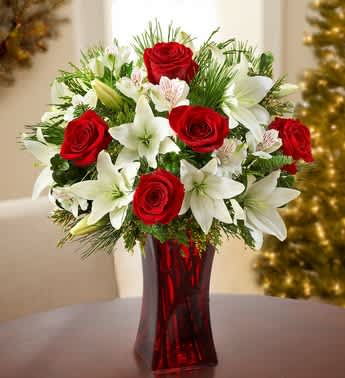 Holiday Magic - Product ID: 99104  Our enchanting bouquet of red roses, white lilies and evergreens delivers all the magic of the holiday seasonâno sleigh required! Hand-designed by our expert florists in a red gathering vase, we guarantee it will leave all the special people in your life feeling merry and bright. Bouquet of red roses, white lilies and alstroemeria, accented with assorted Christmas greens Lilies may arrive in bud form and will open to full beauty over the next 2-3 days Hand-arranged in a red glass gathering vase; measures 9&quot;H Large arrangement measures approximately 19&quot;H x 13&quot;L Medium arrangement measures approximately 18&quot;H x 11.5&quot;L Small arrangement measures approximately 17&quot;H x 10&quot;L Our florists select the freshest flowers available, so colors and varieties may vary due to local availability