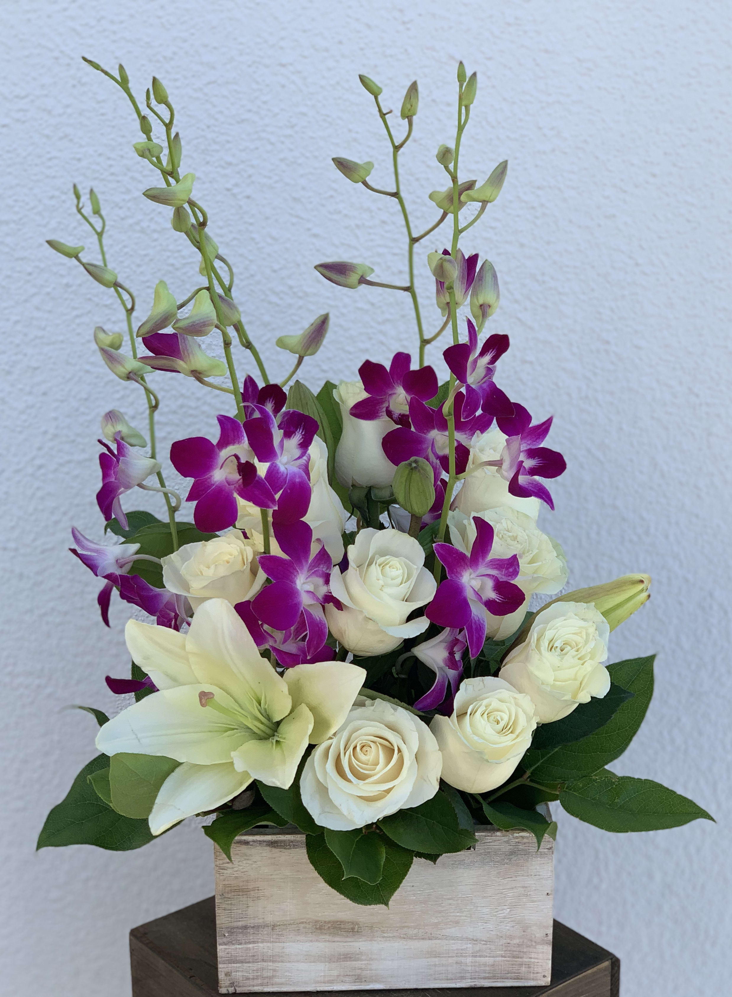 It's the Simple Things It's the Simple Things - A simple arrangement of white roses, white lilies, and purple dendrobium orchids in a wooden box.