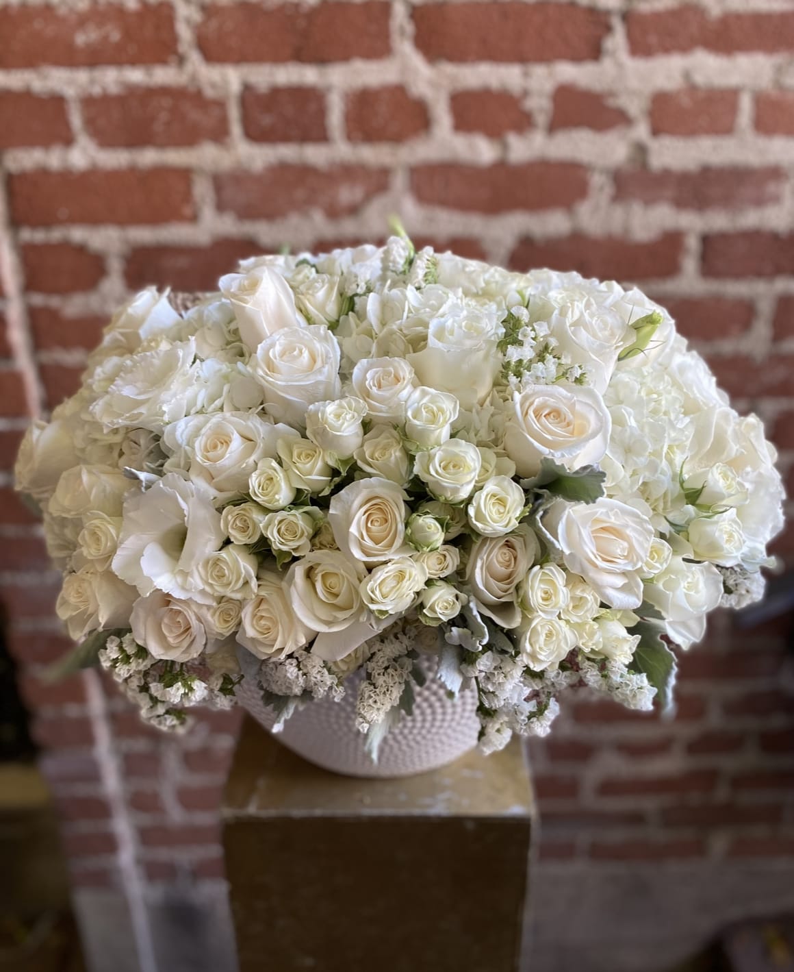Dreams - SCV Florist - &quot;Dreams&quot; is an elegant floral arrangement featuring pristine white roses and delicate white spray roses, artfully displayed in a classic Italian vase. The soft, pure tones of the roses evoke serenity and timeless beauty, while the vase’s design adds a touch of European sophistication. Perfect for weddings, anniversaries, or to convey heartfelt sentiments, this arrangement embodies grace and refinement, making it a stunning centerpiece or gift for any occasion.