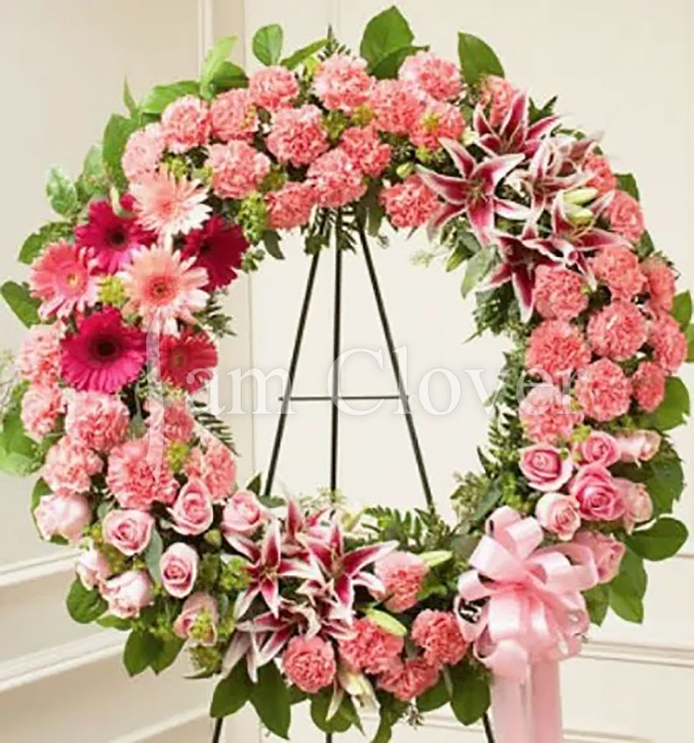 Pink Wreath - This pink funeral wreath is a delicate and heartfelt tribute, symbolizing love, compassion, and remembrance.  Fulfill your floral needs at I Am Clover in Ramona, CA, and experience the difference in quality, freshness, and care that comes with ordering locally.   Disclosure: In some instances, our photo may represent an overall look and include a one-of-a-kind vase which cannot be exactly replicated. Occasional substitutions of flowers and/or containers happen due to weather, seasonality and market conditions. We will ensure that the style, theme and color scheme of your arrangement is preserved and will only substitute items of equal value or higher value.  Delivery: 2:30pm - 6:30pm Same Day Orders may take at least 6 hours to process and deliver Morning and Specific Delivery Time Requests:  will be charged a $15 convenience fee. Specific delivery times are acknowledged and we will do our best to accommodate, however we cannot guarantee on time delivery due to unforeseen events.  Gate Codes are mandatory for our delivery drivers to enter residential or commercial buildings. If you don’t know the gate code for a delivery, please contact the recipient and provide us with it or our driver can contact the recipient before beginning a delivery route to obtain the code. Our drivers will only wait five minutes outside the gate for a callback. If a driver has to leave a property, the delivery is reassigned for the next day and may charge an additional delivery fee.   Thank you!
