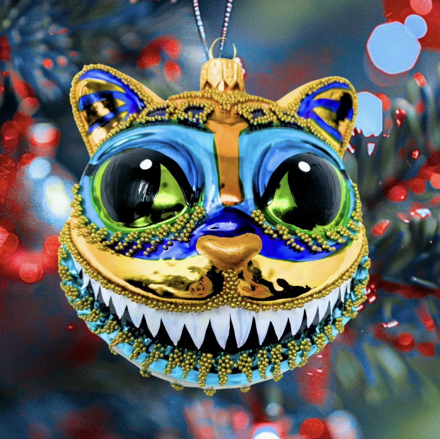 Cheshire Cat Oranament - The Handblown Cheshire Cat Ornament by Kenzies of London for Chartreuse by Roje is a stunning piece of craftsmanship, meticulously handcrafted by skilled artisans in Poland. Each ornament begins as a carefully crafted mold, made from clay and cast in metal. This mold is then used to shape the glass, which is expertly blown into a whimsical figure. The result is a charming and intricate Cheshire Cat that captures the playful spirit of the iconic character. Expert painters spend hours hand-painting each ornament, bringing every detail to life with delicate precision. Due to the hand-painted nature of the ornament, slight variations in color and pattern may occur, adding to the unique charm of each piece. Made using traditional Polish blown glass techniques, this ornament is crafted from heirloom-quality glass, ensuring it will be cherished for years to come. Measuring approximately 4x3.5 inches, it comes with a ribbon for hanging and is accompanied by a branded hang tag and a Certificate of Authenticity, making it a perfect addition to any collection or a thoughtful gift for someone special.
