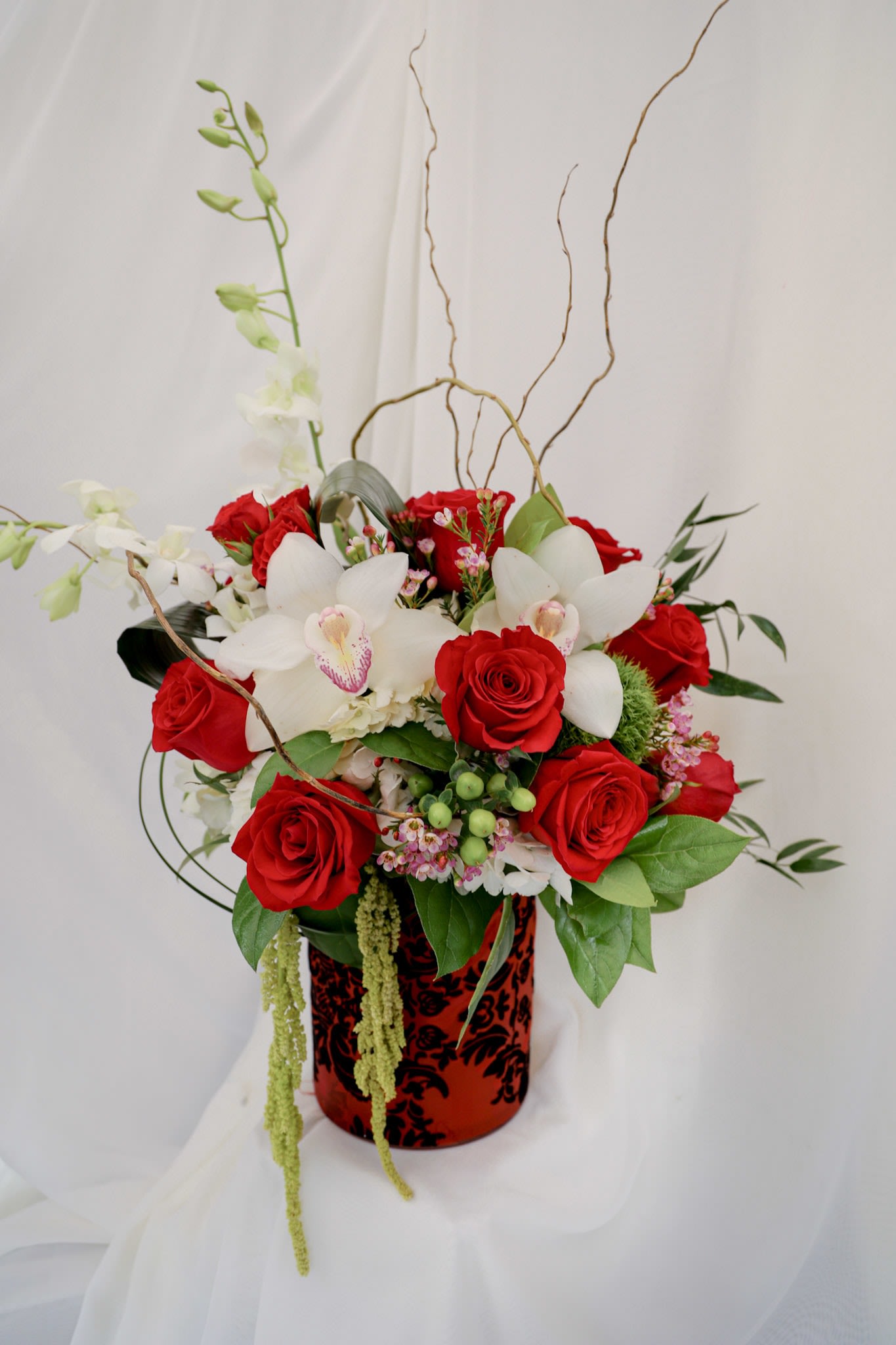 Winter Kiss Winter Kiss - This elegant arrangement is composed of orchids, a dozen red roses, and a variety of classic greenery.