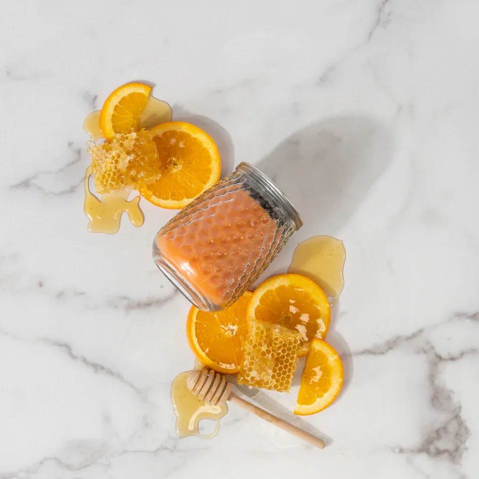Orange & Honey Candle Orange & Honey Candle - With a clear, glass hobnail textured jar and a silver lid, our Signature Candle is the perfect match for any style. Fill your home with inviting Greenleaf fragrances that make any space feel cozy! What Makes it Special: Beautiful fragrance created in-house by a team of professional perfumers Fragrance: Orange & Honey Fragrance Family: Fruit & Vine Fragrance Description: Revitalizing through and through, Orange & Honey lands the senses amidst a picturesque orange grove where clusters of nature's candy gleam in ripened glory. Use and Care: Burn within sight, Always trim wick to 1/4 in before lighting candle Keep candle on a level surface away from drafts Allow the wax to pool to the edge of the glass before extinguishing the flame Avoid dropping debris, such as wick trimmings, into the wax Extinguish the candle when your wax level reaches 1/4 inch