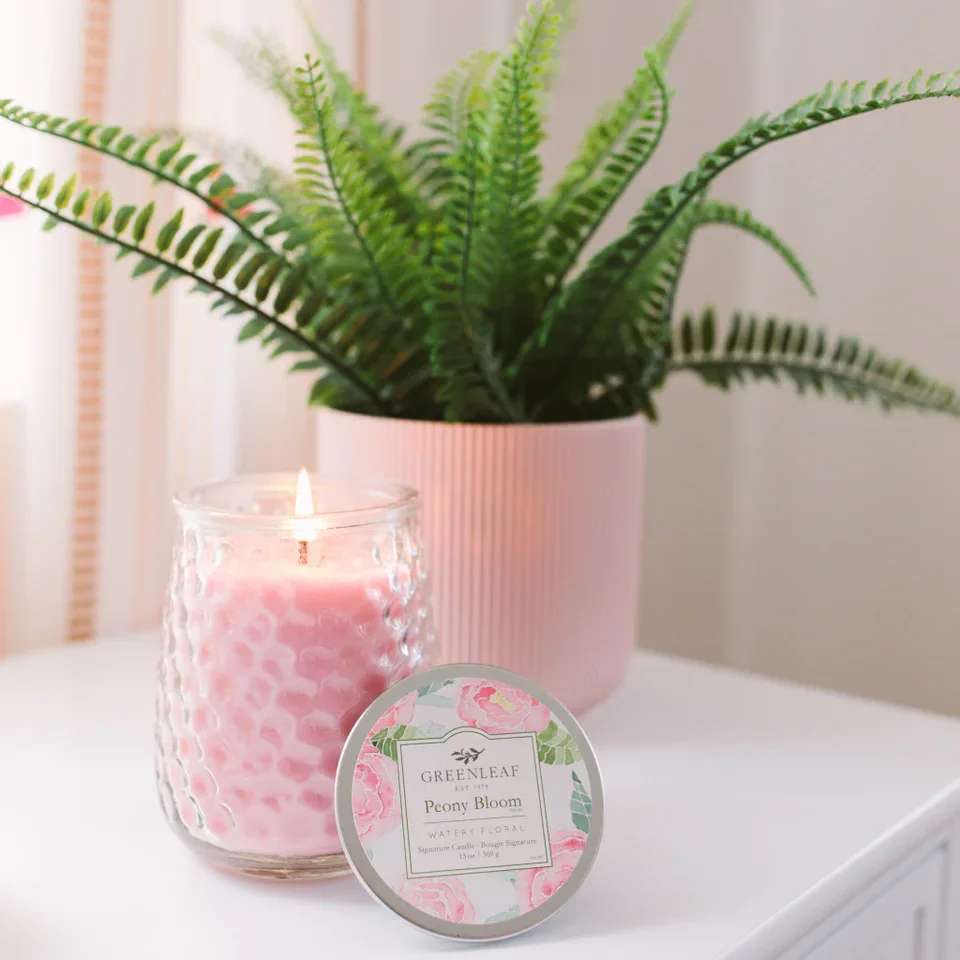 Peony Bloom Candle Peony Bloom Candle - With a clear, glass hobnail textured jar and a silver lid, our Signature Candle is the perfect match for any style. Fill your home with inviting Greenleaf fragrances that make any space feel cozy! What Makes it Special: Beautiful fragrance created in-house by a team of professional perfumers Fragrance: Peony Bloom Fragrance Family: Floral Fragrance Description: With bright, beautiful blooms and energizing green grasses, Peony Bloom is truly exhilarating and unbelievably romantic. Use and Care: Burn within sight, Always trim wick to 1/4 in before lighting candle Keep candle on a level surface away from drafts Allow the wax to pool to the edge of the glass before extinguishing the flame Avoid dropping debris, such as wick trimmings, into the wax Extinguish the candle when your wax level reaches 1/4 inch