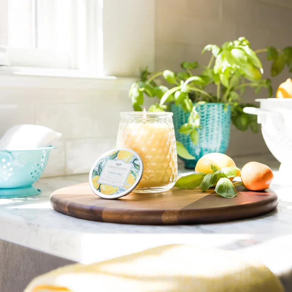 Citron Sol Candle Citron Sol Candle - With a clear, glass hobnail textured jar and a silver lid, our Signature Candle is the perfect match for any style. Fill your home with inviting Greenleaf fragrances that make any space feel cozy! What Makes it Special: Beautiful fragrance created in-house by a team of professional perfumers Fragrance: Citron Sol Fragrance Family: Fresh & Clean Fragrance Description: Clean, radiant, and unbelievably fresh, Citron Sol makes you feel like you're strolling through a citrus grove on a bright, sunny day. Use and Care: Burn within sight, Always trim wick to 1/4 in before lighting candle Keep candle on a level surface away from drafts Allow the wax to pool to the edge of the glass before extinguishing the flame Avoid dropping debris, such as wick trimmings, into the wax Extinguish the candle when your wax level reaches 1/4 inch Specifications Volume: 13 oz Lifespan: 90-100 hours Product Size (inches): 3.75l x 3.63w x 4.75h Package Weight (pounds): 1.75