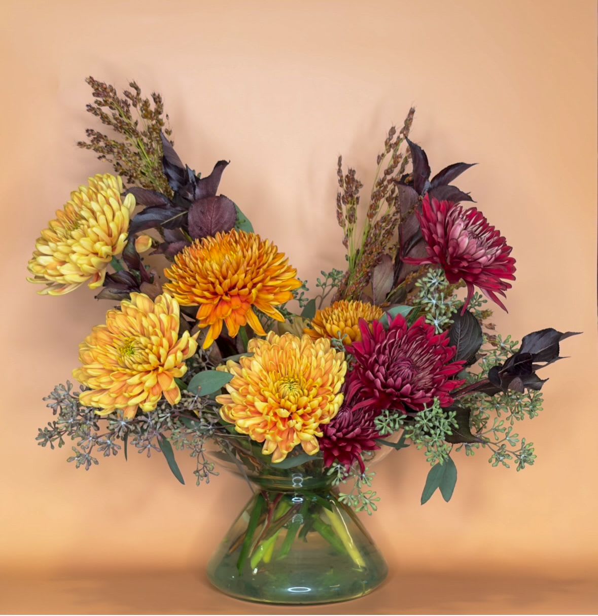 Rustic Harmony Rustic Harmony - Capture the essence of autumn with our Rustic Harmony arrangement, a beautiful blend of muted, traditional fall colors. This loose and whimsical design is artfully crafted in a fluted recycled glass vase, showcasing an array of textures and warm tones that evoke the cozy ambiance of the season. Featuring an assortment of chrysanthemums complemented by lush foliage, this arrangement brings a sense of tranquility and sophistication to any space. Perfect as a centerpiece for seasonal gatherings or a thoughtful gift, Rustic Harmony is a timeless expression of autumn’s charm from Bloom & Thorn.