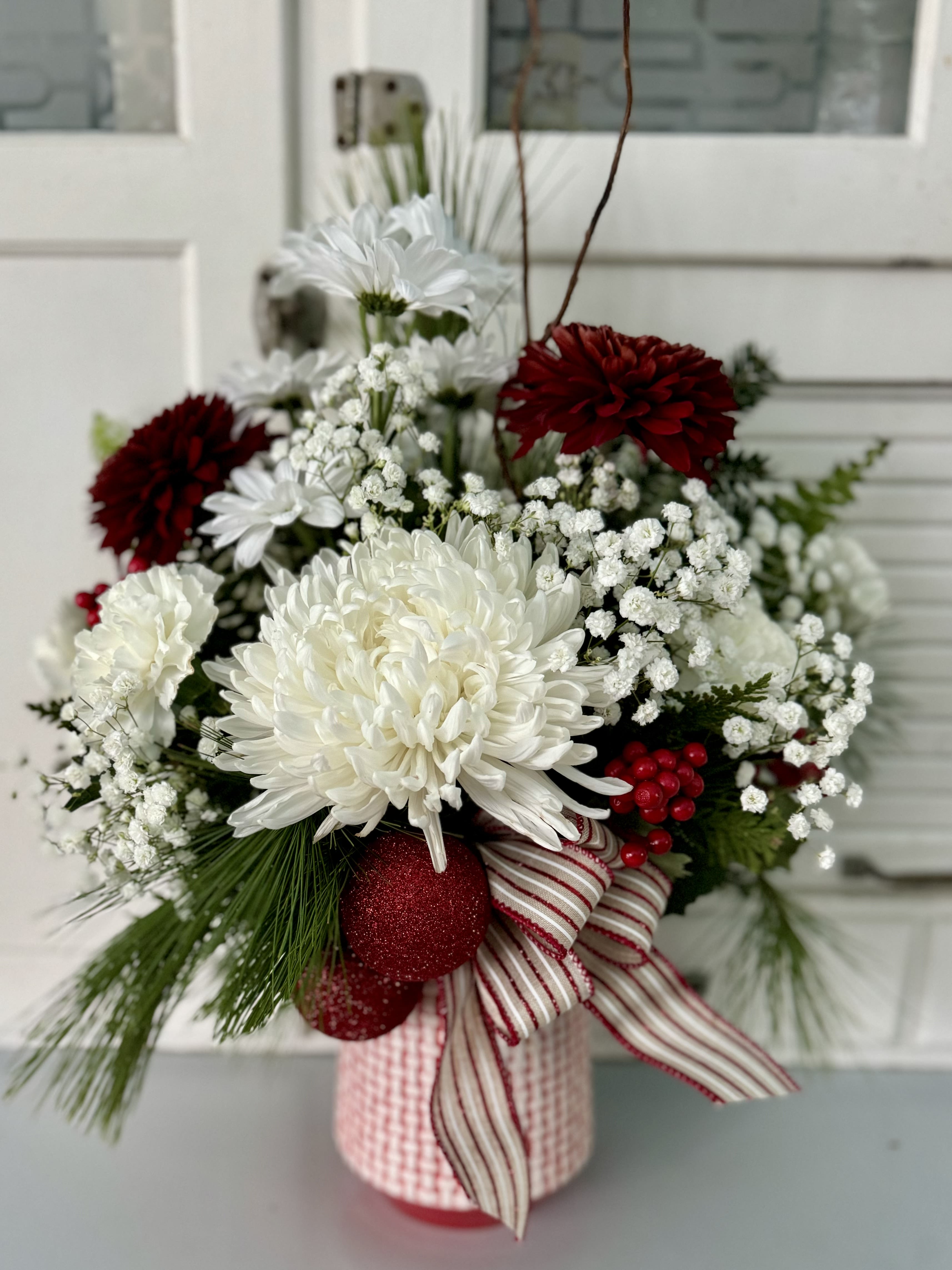 Festive Frostbite Festive Frostbite - With rich red and white tones, this arrangement evokes the spirit of a snowy winter's day. Seasonal greenery and glittering embellishments complete the cheerful, cozy aesthetic.