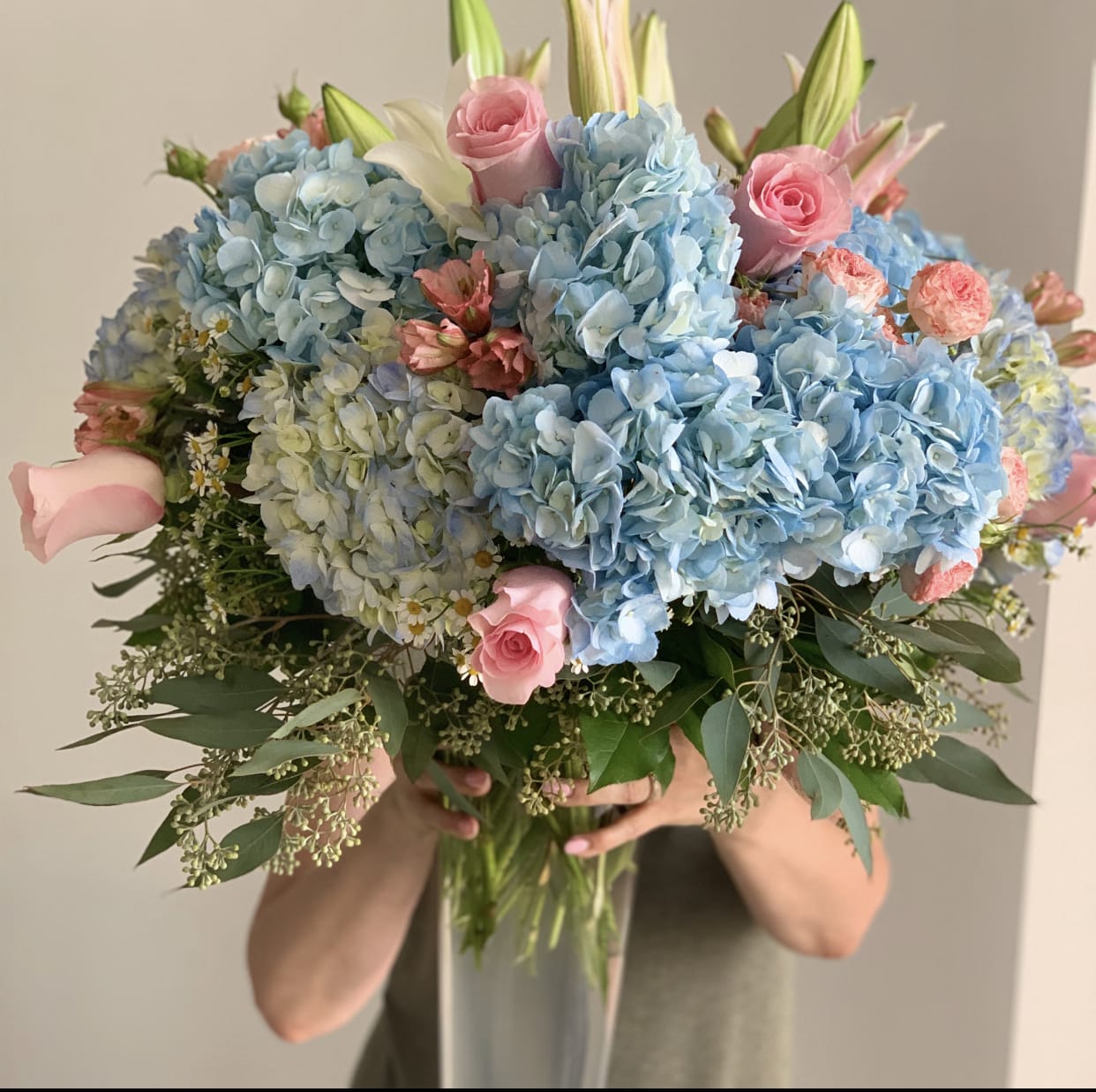 Flower Cloud  - Gorgeous blue hydrangeas with pink roses and lilies will uplift you for no reason! Large and by all and beautiful. Long lasting -because we know the secret. :)  In some instances, our photo may represent an overall theme or look and include a one-of-a-kind vase which cannot be exactly replicated. The actual bouquet may not precisely match the photo, its temperament will. Substitutions of flowers and/or containers happen due to weather, seasonality and market conditions which may affect availability. If this is the case with the gift you’ve selected, we will ensure that the style, theme and color scheme of your arrangement is preserved and will only substitute items of equal value or higher value.  