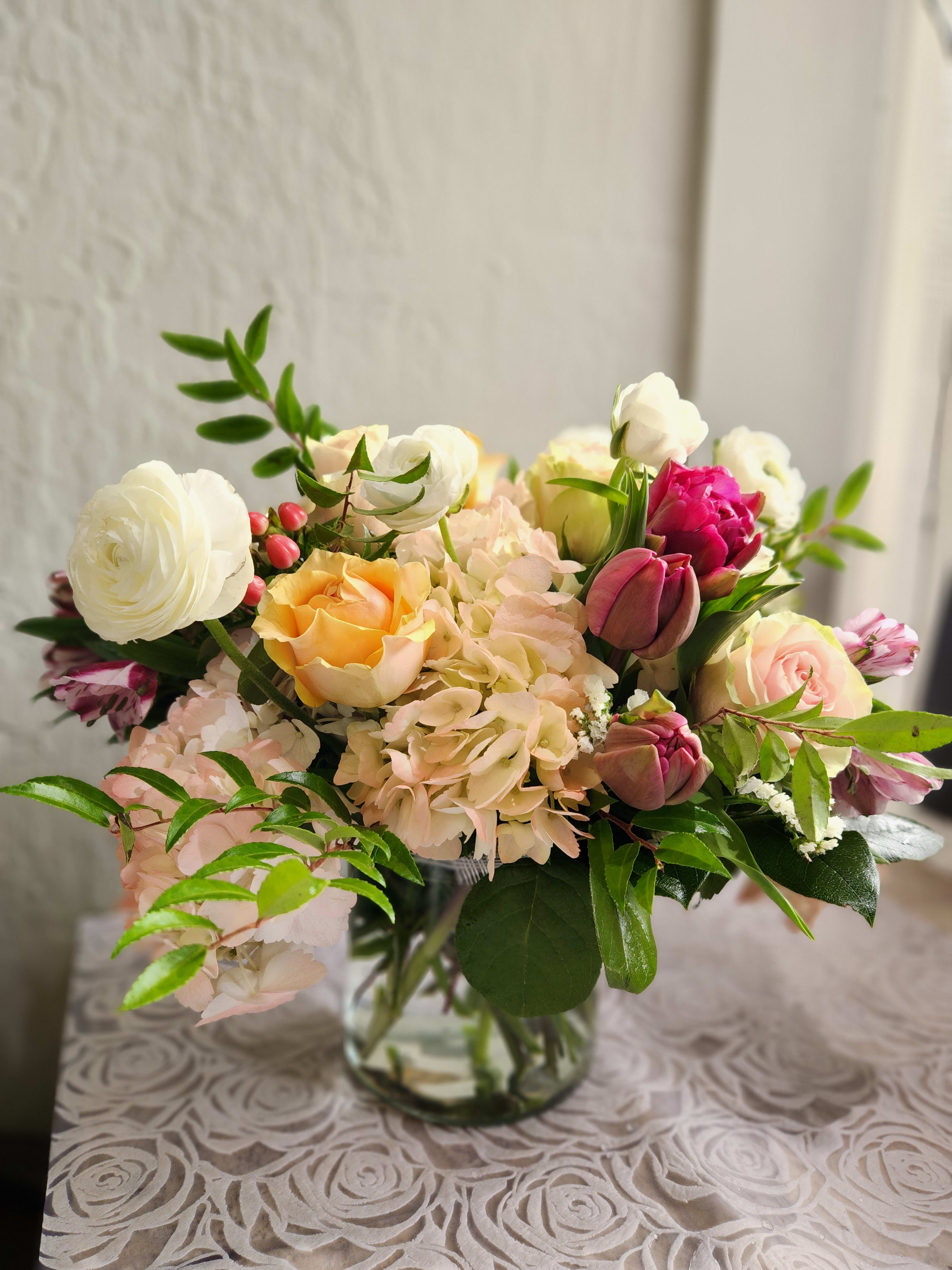 Gabriella Arrangement  - A beautiful spring mix in with hydrangeas, roses, tulips, and ranunculus if in season.  This is arrangement is in a cylinder or cube style vase low and lush with less greens and filler.  This design is about 8&quot;to 12&quot; height including vase. 
