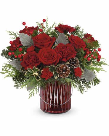 Teleflora's Merry Glow Bouquet - Illuminate your holiday festivities with this enchanting Christmas bouquet, elegantly arranged in a red glass lantern. Later, it doubles as a beautiful candleholder, bringing a warm and festive glow to your home décor. Teleflora's Merry Glow Bouquet showcases maroon carnations, miniature red carnations, variegated holly, dusty miller, noble fir, and cedar, accented with festive flair. Delivered in  Merry Glow Lantern, it brings warmth and elegance to holiday celebrations. Orientation: All-Aro