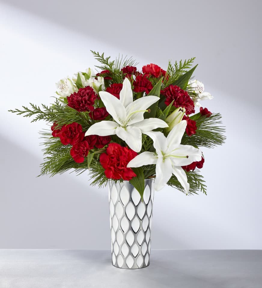 The FTD® Holiday Elegance™ Bouquet: 17-C9s The FTD® Holiday Elegance™ Bouquet: 17-C9s - The FTD® Holiday Elegance™ Bouquet is a stylish way to express your love and wonderment for the Christmas season to your special recipient. As magical as the first snowfall, this stunning fresh flower arrangement brings together rich red roses and carnations with burgundy carnations and mini carnations to create a sense of drama when paired with showy white LA Hybrid Lilies and white Peruvian Lilies, all accented perfectly with fragrant holiday greens. Presented in a modern white ceramic vase with an attractive layered feathered design throughout to add to the texture of this piece, this Christmas bouquet is a wonderful way to send our season's greetings to friends, family, and co-workers this holiday season.