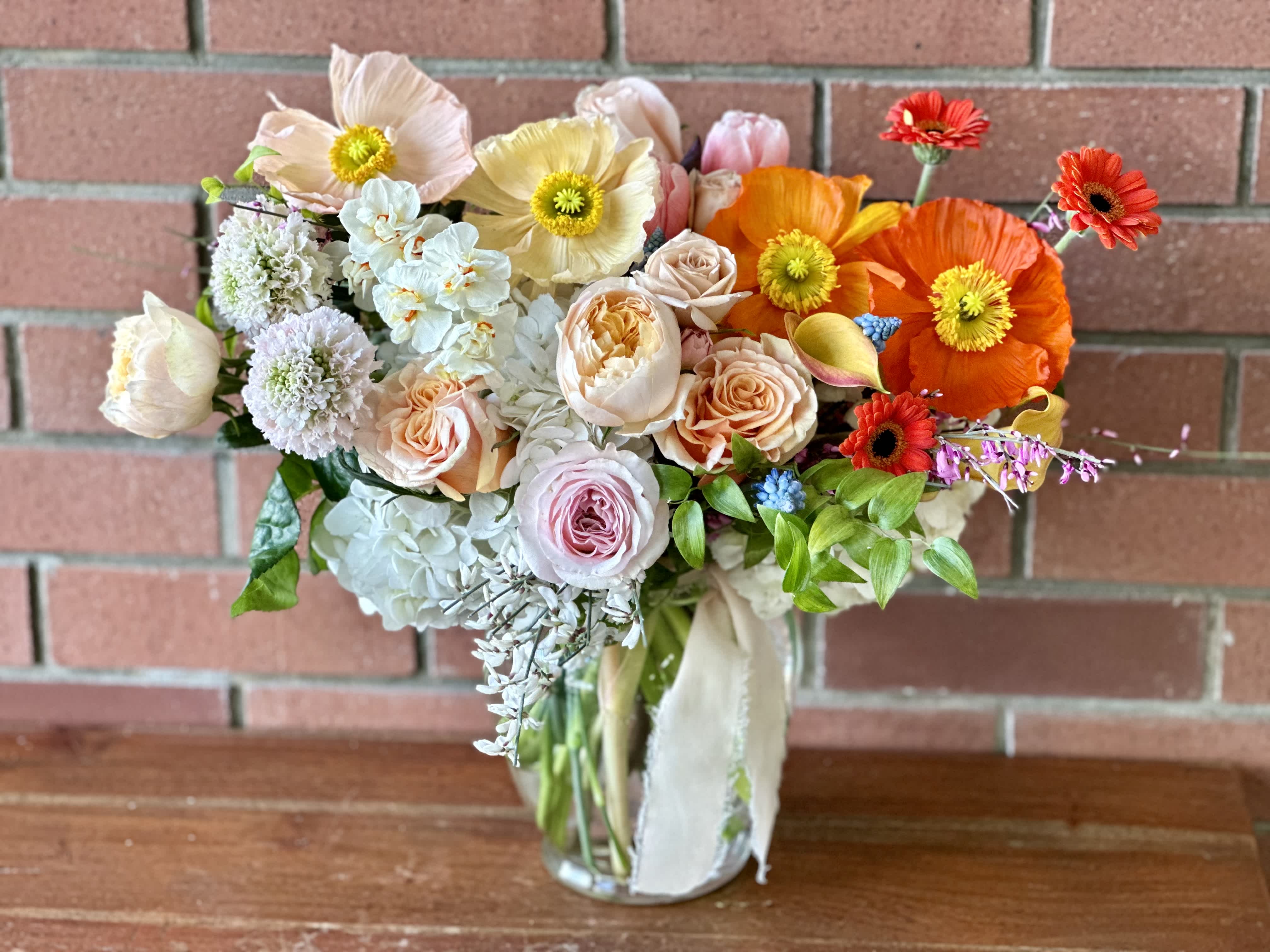 Blooming Spring Gardens Bouquet Blooming Spring Gardens Bouquet - In season now the gorgeous Icelandic Poppies paired with hydrangeas, garden roses, tulips, daffodils, scabiosa and other spring lush flowers arranged in a clear vase wrapped with soft chiffon ribbons.