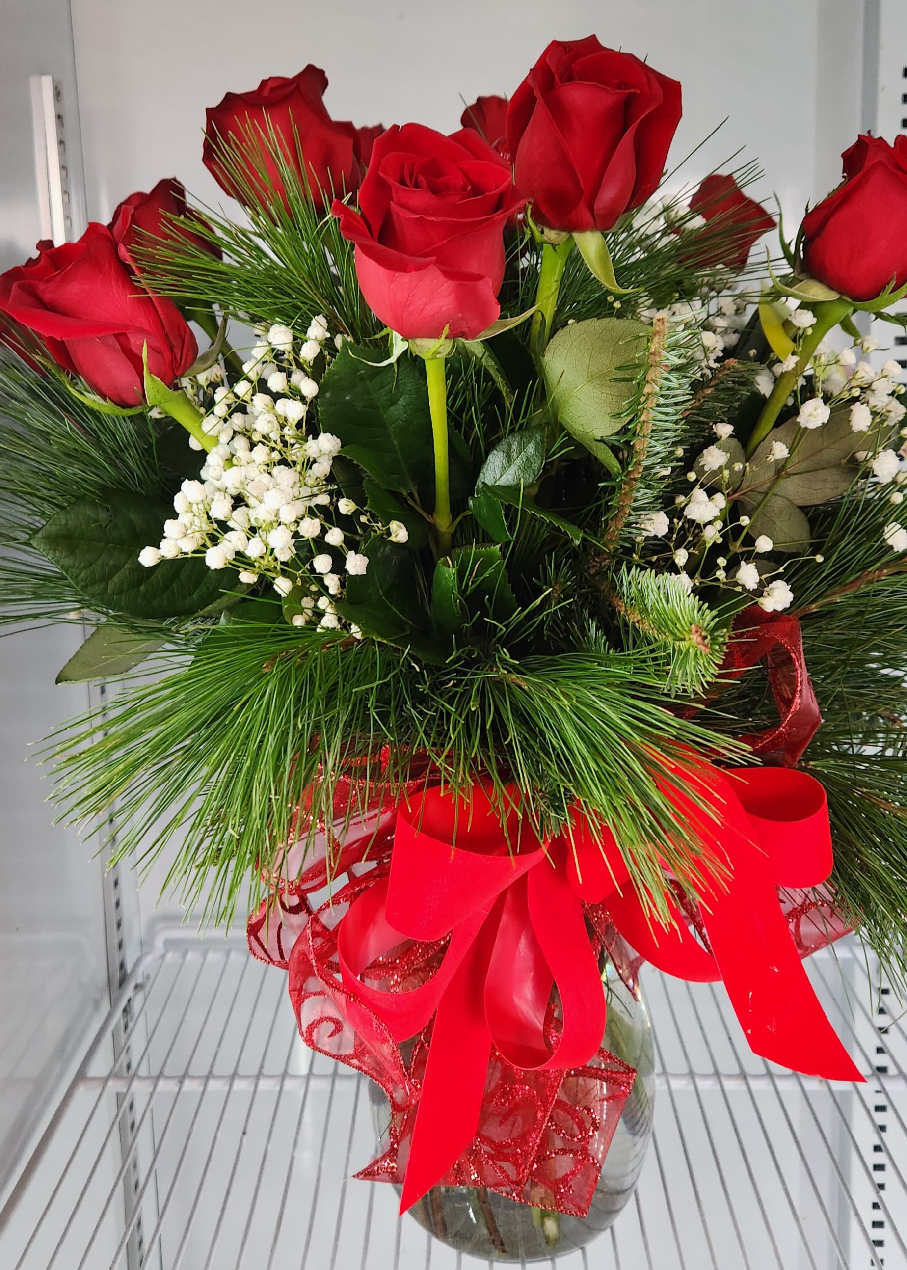 PINE AND ROSES PINE AND ROSES - 1 dozen roses orange in a forest of mixed evergrevergreen foliage.