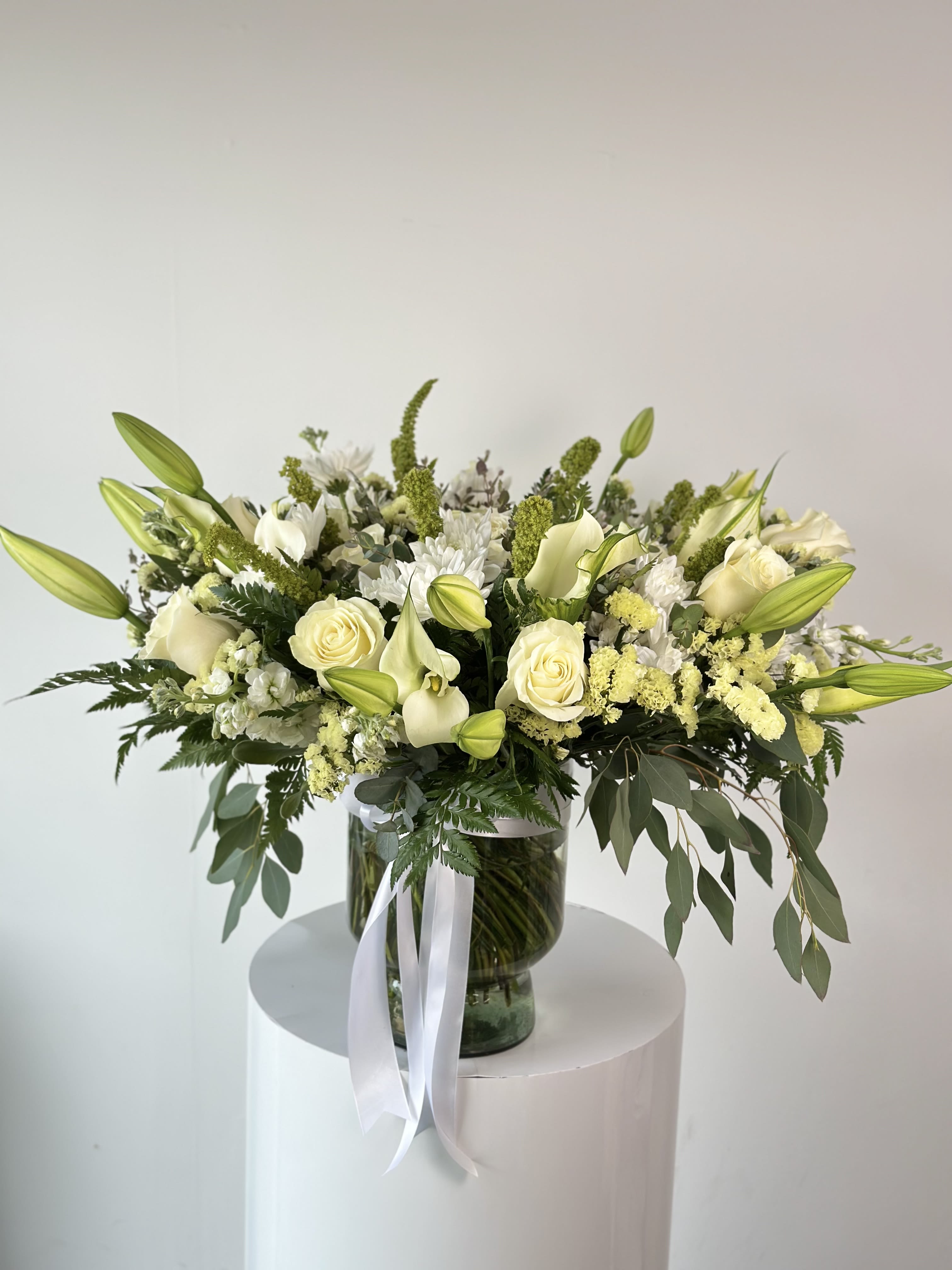 White Symphony - A breathtaking display of elegance.  This giant white floral arrangement is an endless beauty and sophistication. Featuring a blend of premium white blooms, hand arranged in a luxurious vase.  Perfect for grand celebrations, weddings, funerals or as a stunning centerpiece.   Arrangement includes: - Glass vase - Fresh seasonal white flowers - Flower care instructions card - Greeting card