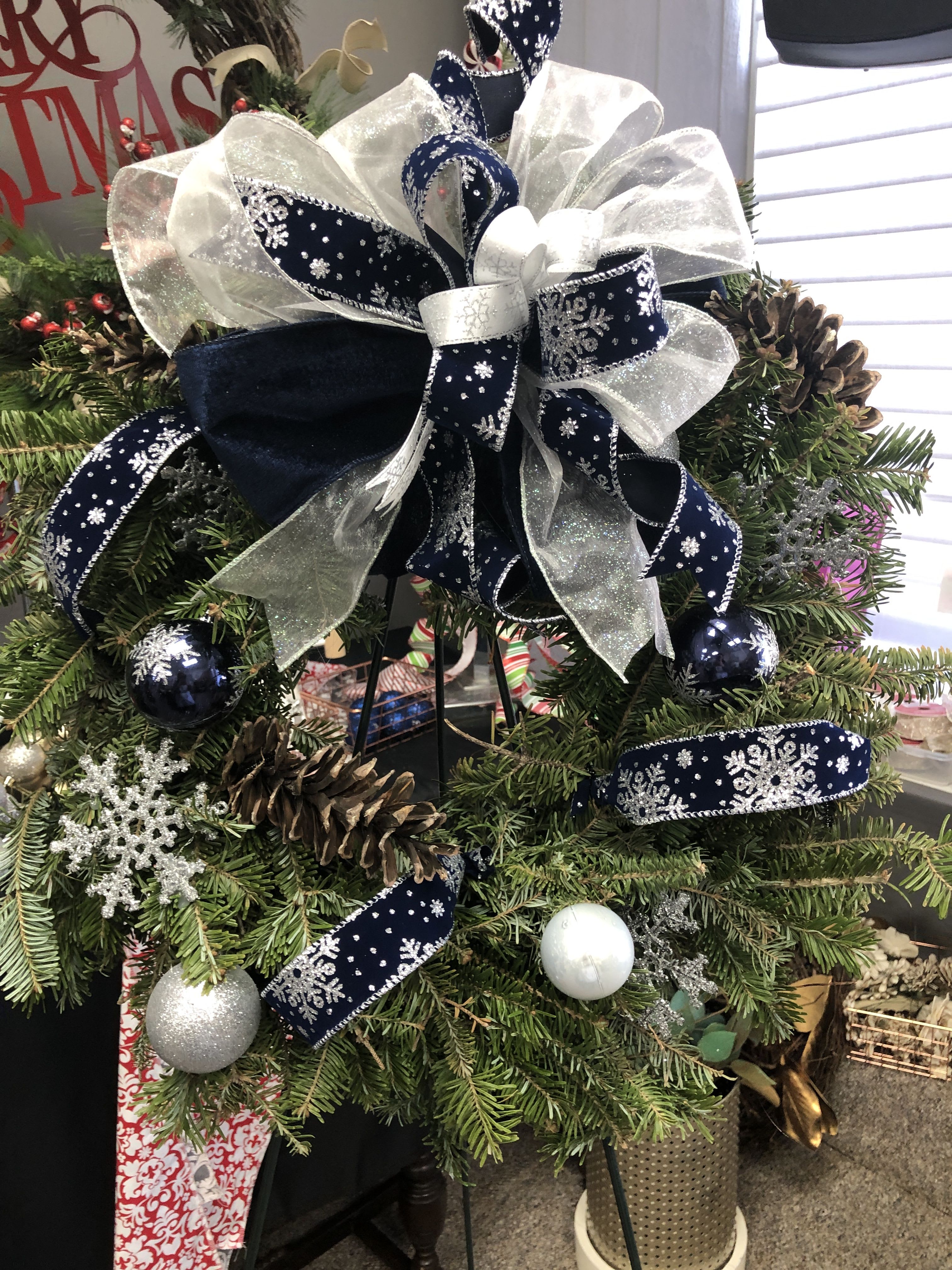 Silver and Blue Snowflake Fresh or live forever wreath Silver and Blue Snowflake Fresh or live forever wreath - A 22 inch wreath that can be real or artificial depending on the customer preference. Accented with snowflakes and navy blue.