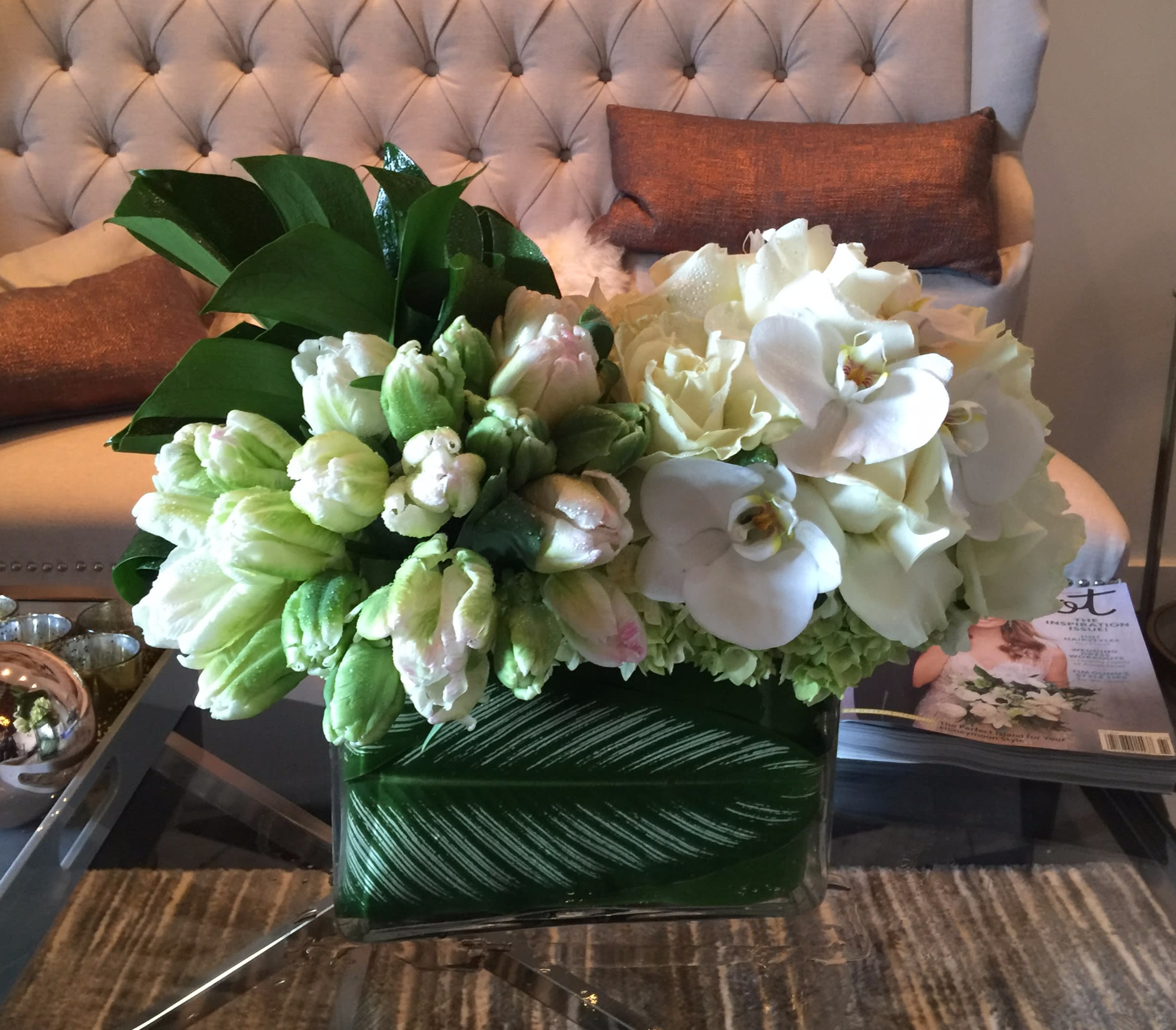 Green Parrot Green Parrot - An arrangement bursting with white and green variegated parrot tulips with white roses and phalaenopsis orchids in a medium vase lined with striped leaves. This modern arrangement will be a delight for anyone and any occasion.