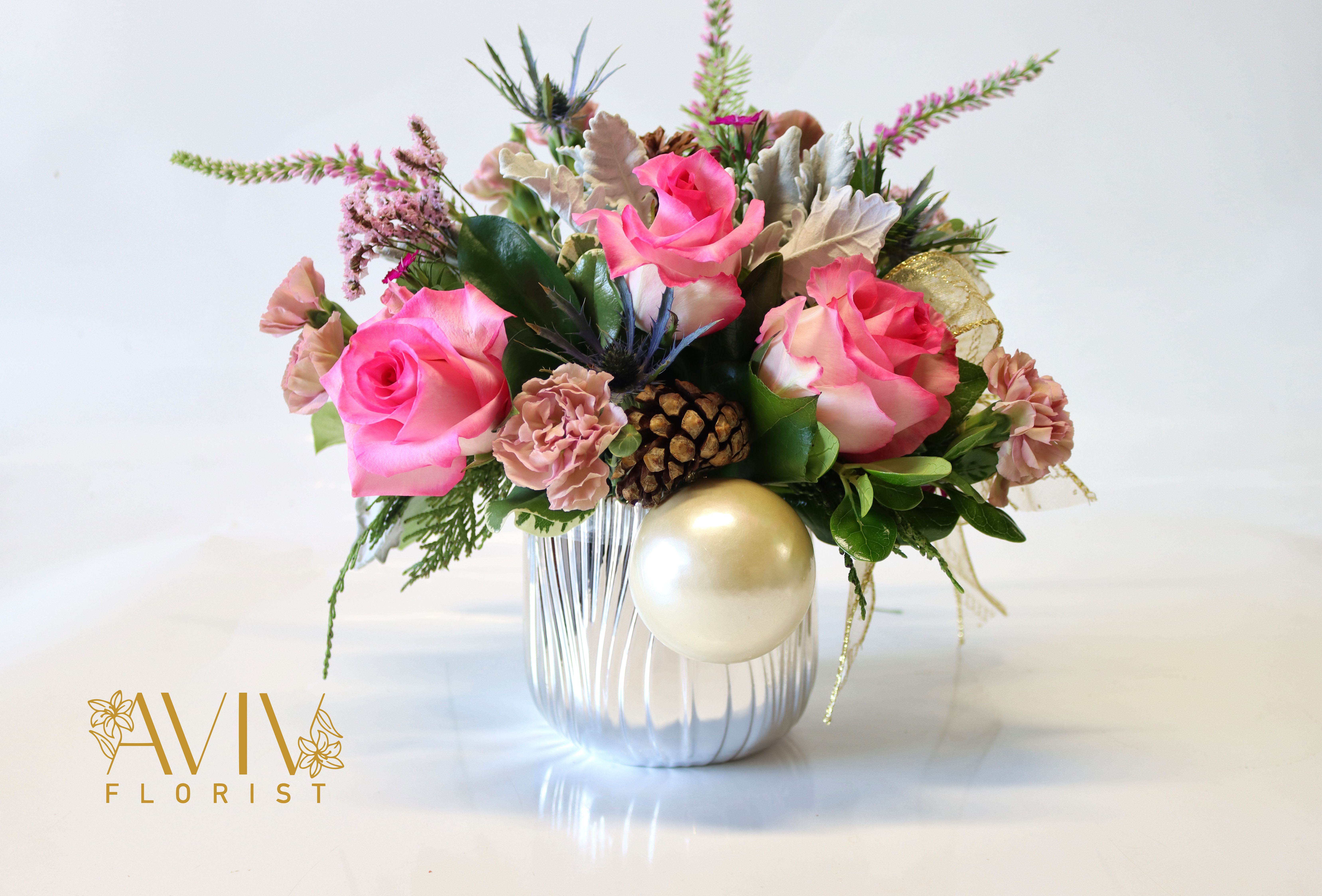 Season Winter Pink  - Celebrating the holidays with our Seasons Pink Bouquet. This joyful bouquet with a silver vase, pink roses, mini carnations, veronicas, and more. It is sure to bring holiday cheer to your home.