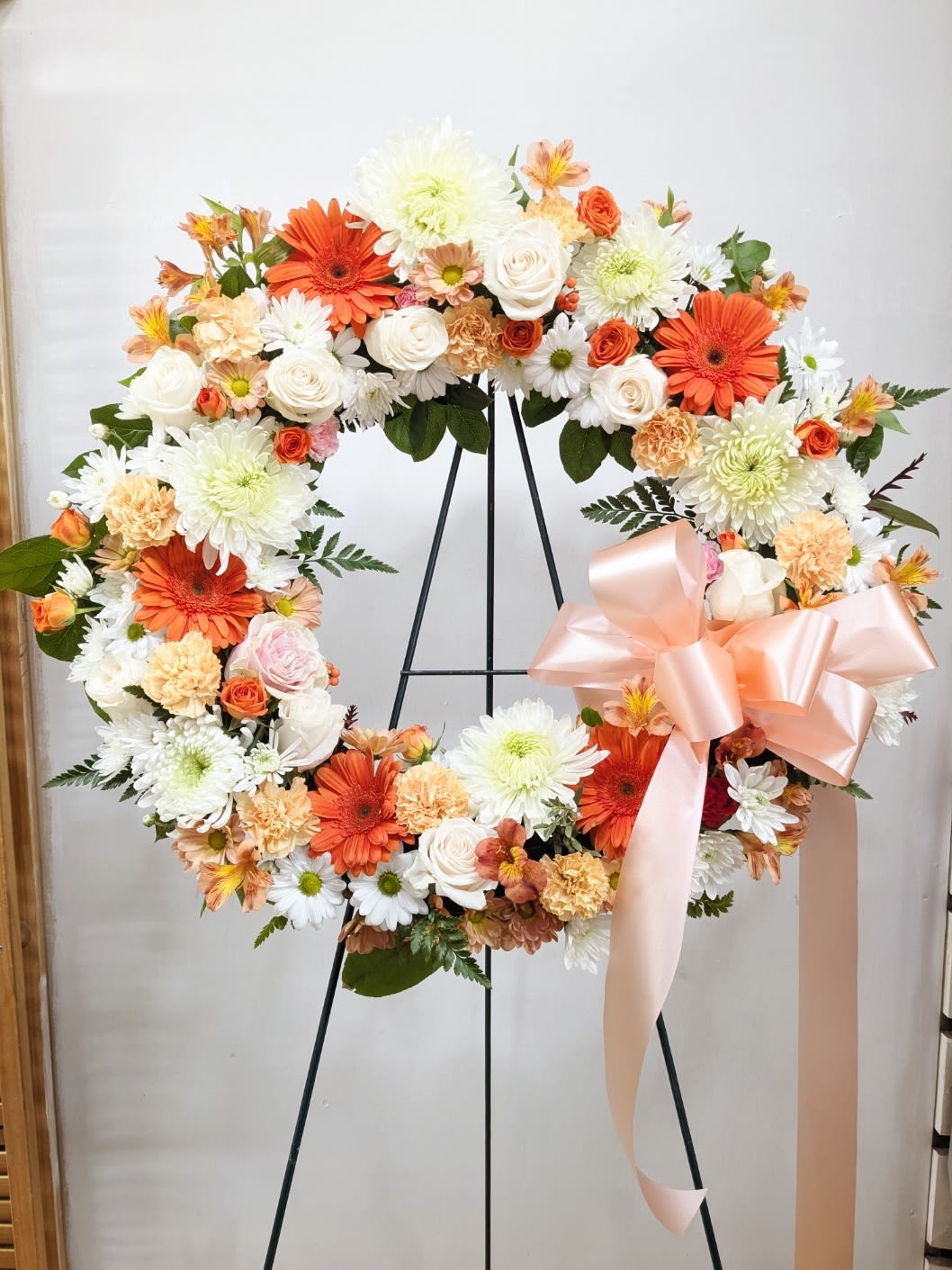 Peaceful Peach Wreath Peaceful Peach Wreath - A beautiful white, peach, some orange tribute wreath that peace, this easel arrangement celebrates a full life and a peaceful passing. Approximate Dimensions: 18"D X 16"H (Standard), 22"D(Deluxe/ Picture size), 25"D(Premium)