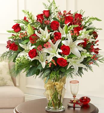 Glorious Christmas Glorious Christmas - Elegance in abundance – that’s our extra-bold, ultra-large Christmas arrangement of fresh and fragrant roses, lilies, snapdragons, hypericum and assorted greens, hand-designed in a stylish glass vase and finished off with festive satin ribbon. Luxurious and lovely.