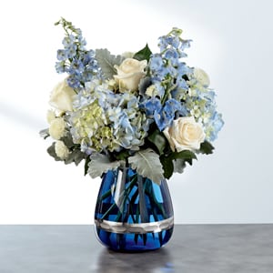 Remembrance - Speak from your heart to theirs with this flower arrangement of white roses and white button poms with blue Bella Donna Delphinium and blue hydrangea, accented with fresh greens.