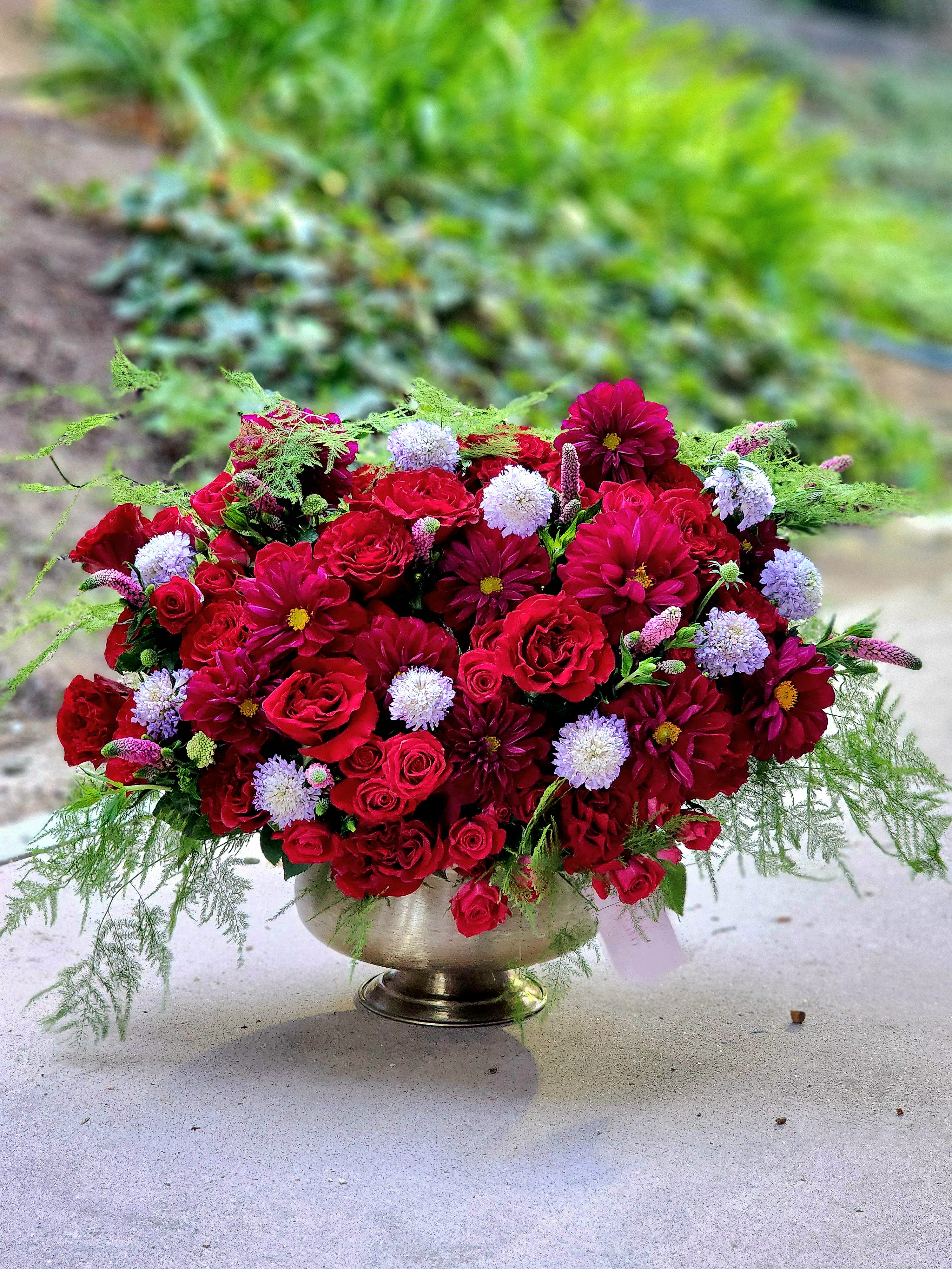 I Found Love - This luxurious arrangement features a stunning combination of deep red roses and vibrant dahlias. Nestled in a chic gold vase and complemented by lush greenery, it’s the perfect centerpiece for upscale events or heartfelt gifts