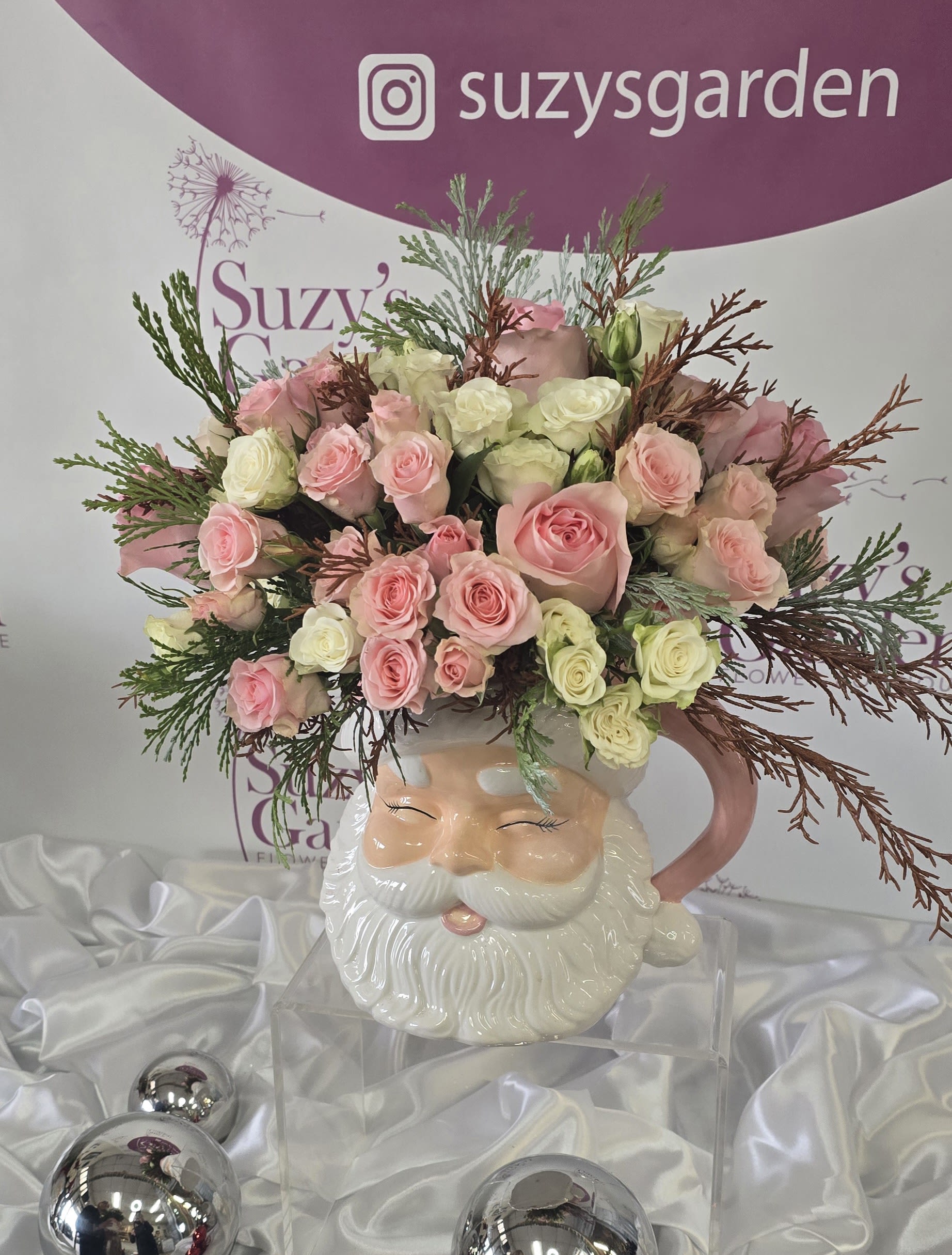 Santa Christmas Arrangment - A festive Santa vase, Christmas flower arrangement featuring roses, surrounded by mixed flowers. Comes with Pink or Red Vase (As shown)