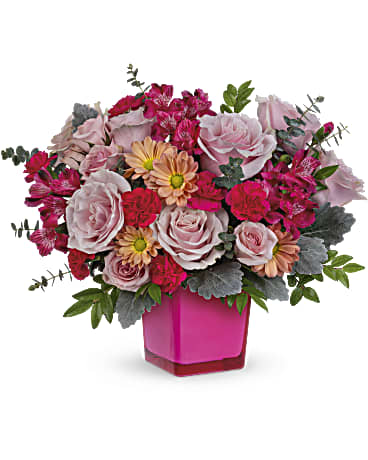 Teleflora's Growing Love Bouquet - Teleflora's Growing Love Bouquet is X's and O's bundled up into a rosy arrangement! This sweet array of blooms is arranged in the Rose Color Splash cube. Pink roses, pink spray roses, hot pink alstroemerias, miniature hot pink carnations, and beige daisy spray chrysanthemums are arranged with dusty miller, huckleberry, and spiral eucalyptus. Delivered in Teleflora's Rose Color Splash Cube.