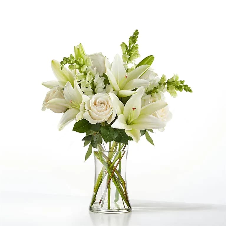 Friendship Eternal - An exuberance of bright and beautiful white blossoms provides an exquisite way to deliver your expressions of sympathy and comfort. This life affirming tribute combines white roses, snapdragons and Asiatic lilies accented by lush greens arranged in a clear glass 8&quot; vase. An excellent choice for sending your condolences to the grieving family or friends.
