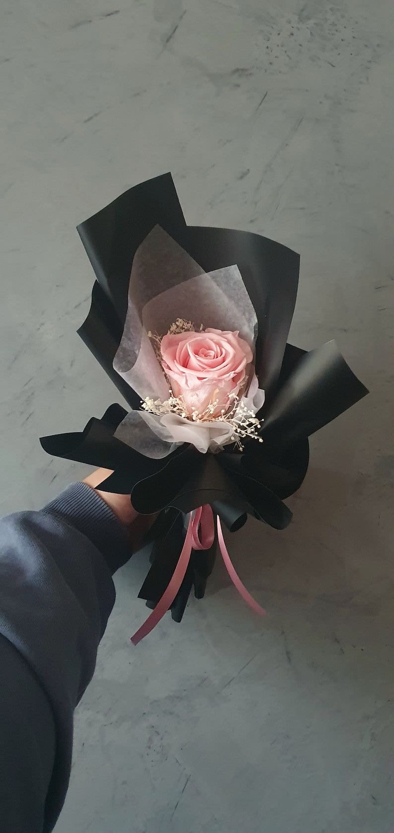 Midnight Blush Rose Midnight Blush Rose - “A Symbol of Elegance and Simplicity Introducing the “Midnight Blush Rose”, a single, stunning pink rose delicately wrapped in sleek black and soft accents of white. This minimalist yet striking arrangement exudes sophistication, mystery, and romance all at once. Perfect for: • Expressions of Love: When words are not enough, this timeless rose says it all. • Special Moments: Ideal for anniversaries, proposals, or thoughtful surprises. • Elegant Gifting: A refined choice for those who appreciate beauty in its purest form. Let one rose tell your story. Order the ‘Midnight Blush Rose’ today and gift a moment they’ll cherish forever.