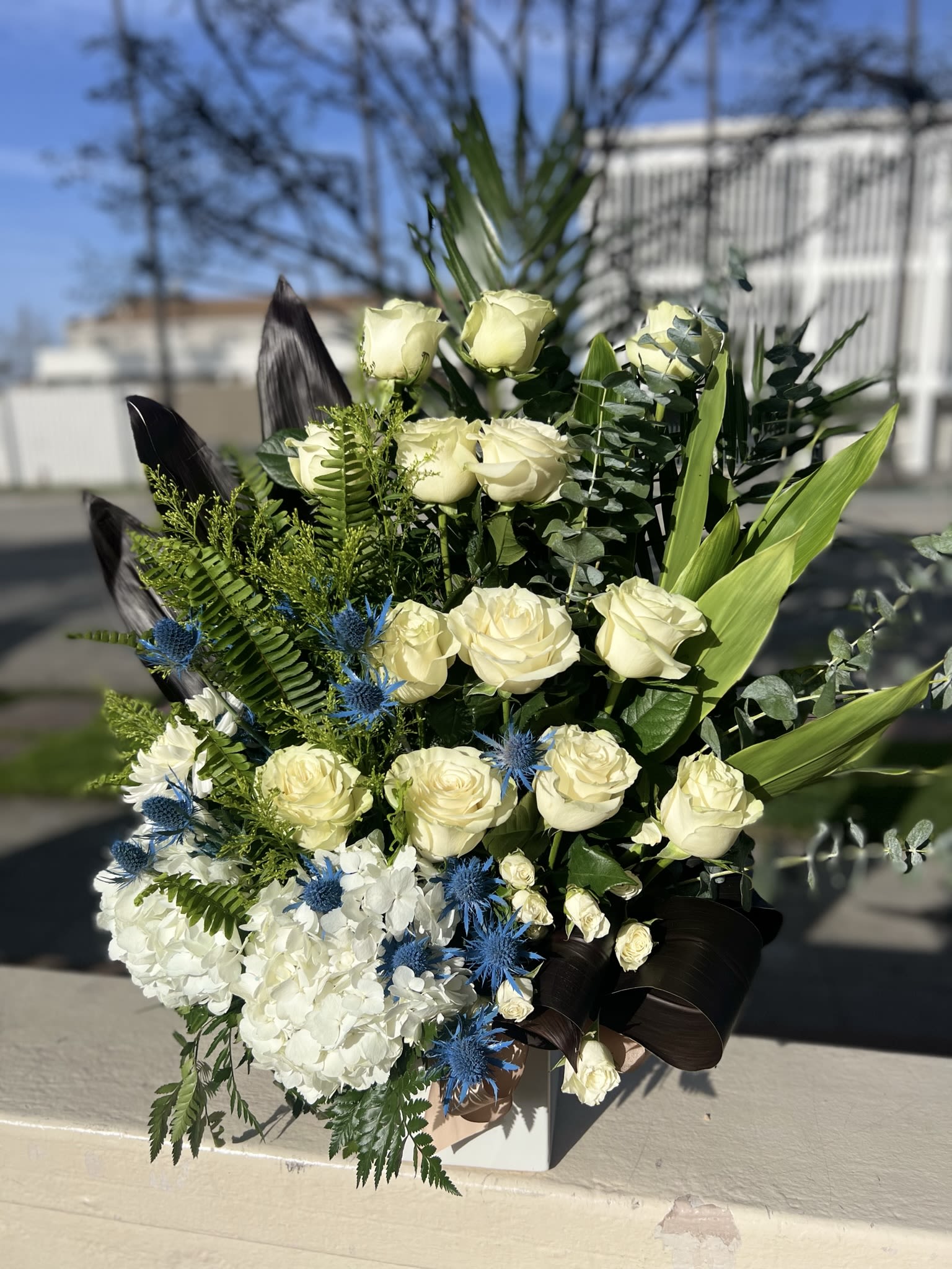 Amelie Cluster Floral Arrangement Amelie Cluster Floral Arrangement - Floral arrangement of 12 white roses, white hydrangea, eucalyptus, lederhosen and filler. 24 inches tall 18 inches wide.
