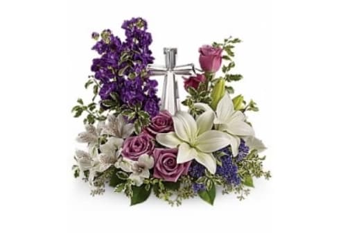 Teleflora's Grace and Majesty - A bouquet to remember. This glorious garden of roses, lilies and alstroemeria surrounds a gleaming cross. It's a radiant, reverent expression of faith that will be appreciated for years to come. Lavender roses, white asiatic lilies, white alstroemeria, purple stock and purple seafoam statice are arranged with fresh pitta negra, seeded eucalyptus and lemon leaf. Delivered with a Cross keepsake. 