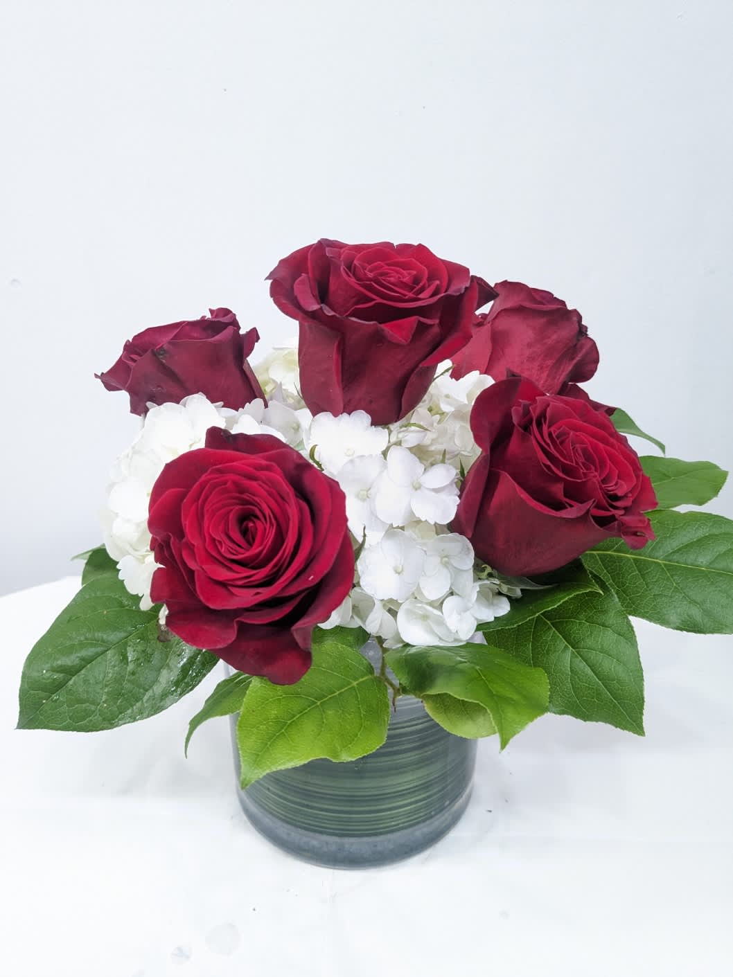 Blossoming Romance - Blossoming Romance is the perfect gift to wish someone a happy birthday or to say thank you.   Arrangement Details:  This arrangement includes 6 red roses, red carnations and white hydrangea in a cylinder vase. APPROXIMATE DIMENSIONS: 12&quot; H X 11&quot; W