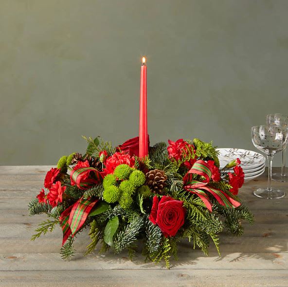 FTD By the Candlelight Centerpiece - Let time fly By the Candlelight centerpiece as new holiday memories are made. What better way to commemorate the joyful homecoming than with classic red roses and lush evergreen accents?  Please Note: The bouquet pictured reflects our original design for this product. While we always try to follow the color palette, we may replace stems to deliver the freshest bouquet possible, and we may sometimes need to use a different vase.