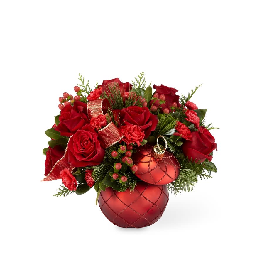 THE FTD® CHRISTMAS MAGIC™ BOUQUET - An elegant combination of red roses, carnations and berries, nestled in a bed of Christmas greens, makes for an arrangement with a magical touch. The Christmas Magic bouquet brings this season favorite blooms for the perfect gift for your loved ones this year; the red ceramic ornament vase is a sparkling keepsake