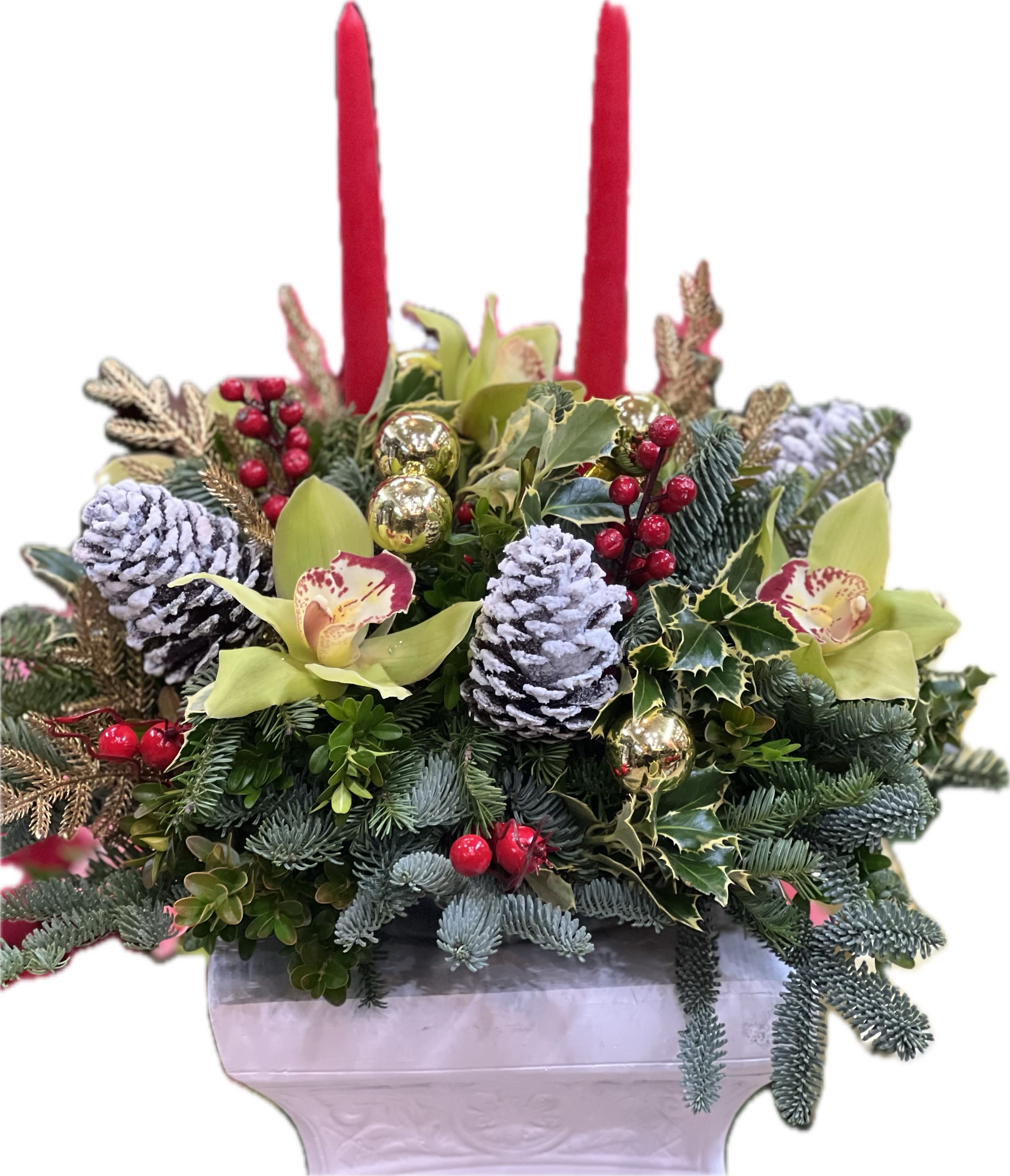 Festive  - This elegant decorative centerpiece features a luxurious blend of natural and festive elements, designed to bring a touch of sophistication to any holiday setting. At its heart is a beautifully crafted boxwood arrangement, accented by the rich, vibrant green of noble fern, creating a lush and inviting look. A striking holly branch, with its bright red berries and glossy leaves, adds a festive pop of color. A tall, graceful candle sits nestled within the greenery, its soft glow enhancing the warmth and charm of the arrangement. Other delicate seasonal decorations, such as sparkling pinecones and shimmering gold accents, complete the piece, making it a perfect centerpiece for holiday dinners or a stunning addition to any festive table