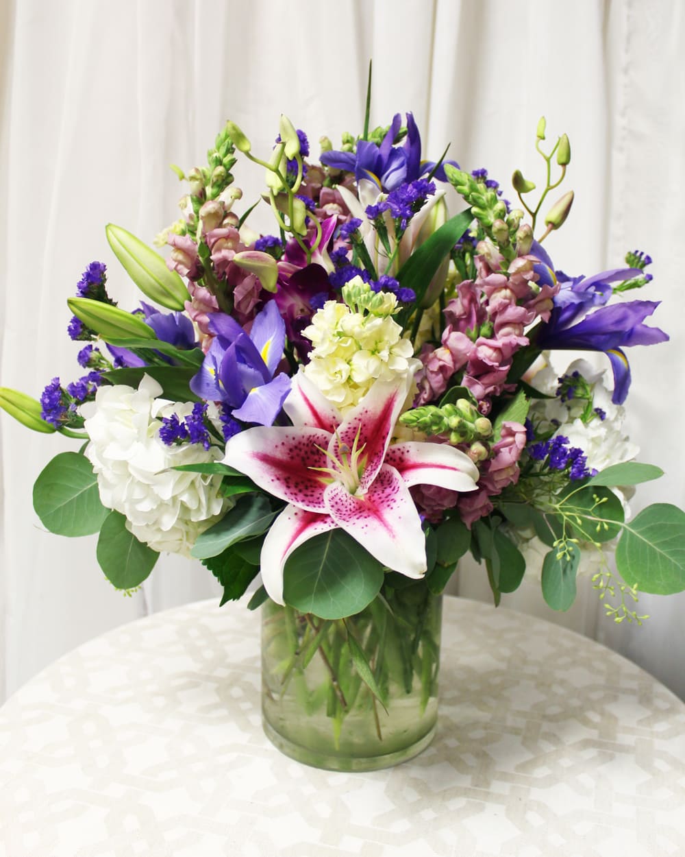 Cool Beauty - An arrangement of vibrant lilies and hydrangeas with the soothing blue of irises.  Key notes for this design are irises and pink/purple colors. 