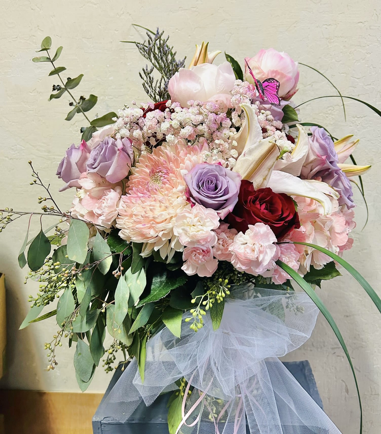 Botanical Bliss - Beautiful pastel arrangement featuring lavender roses, white mums, lilies, carnations, and green accents. 