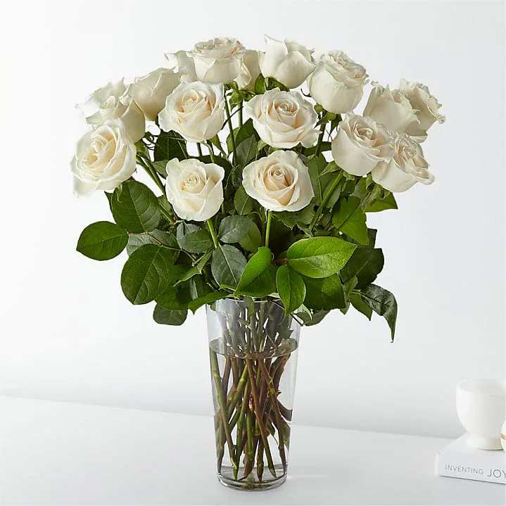White Radiance White Radiance - Exuding timeless elegnce and grace, this arragement of pristine white roses captures the essence of purity and sophistication. Each stem is carefully selected and arranged in a clear vase to allow the natural beauty of the blooms to shine.