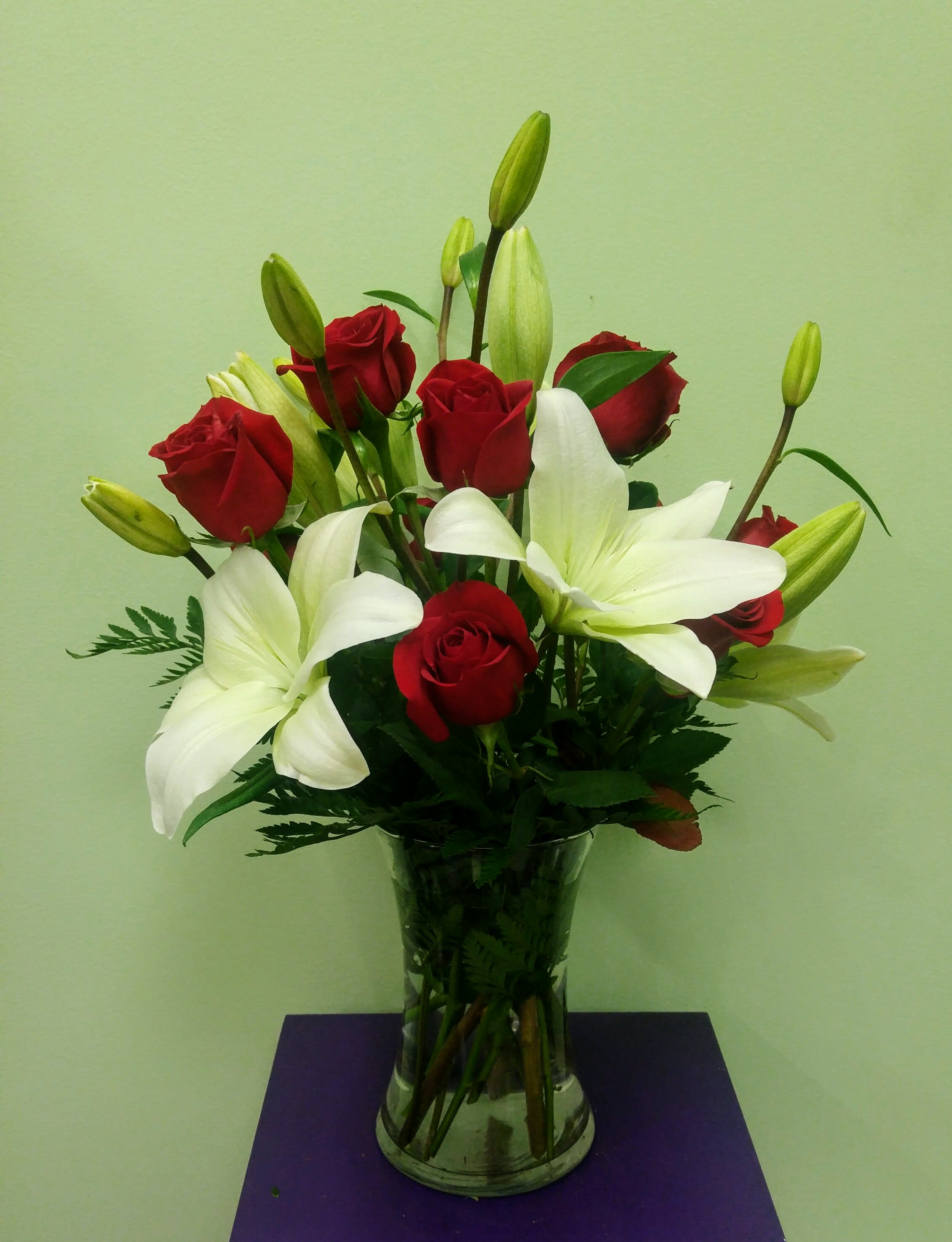 Elegant Red and White - A simple yet extremely elegant arrangement. An assortment of fresh red roses and pure white lilies professionally designed in a clear glass vase will have them blown away. 