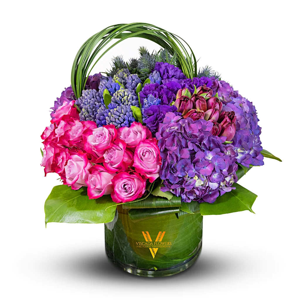 Passion At Dawn - This captivating bouquet features pink roses, purple muscaris and hydrangeas, Cabernet tulips, blue sea holly, and greens. Perfect for adding a touch of passionate beauty.